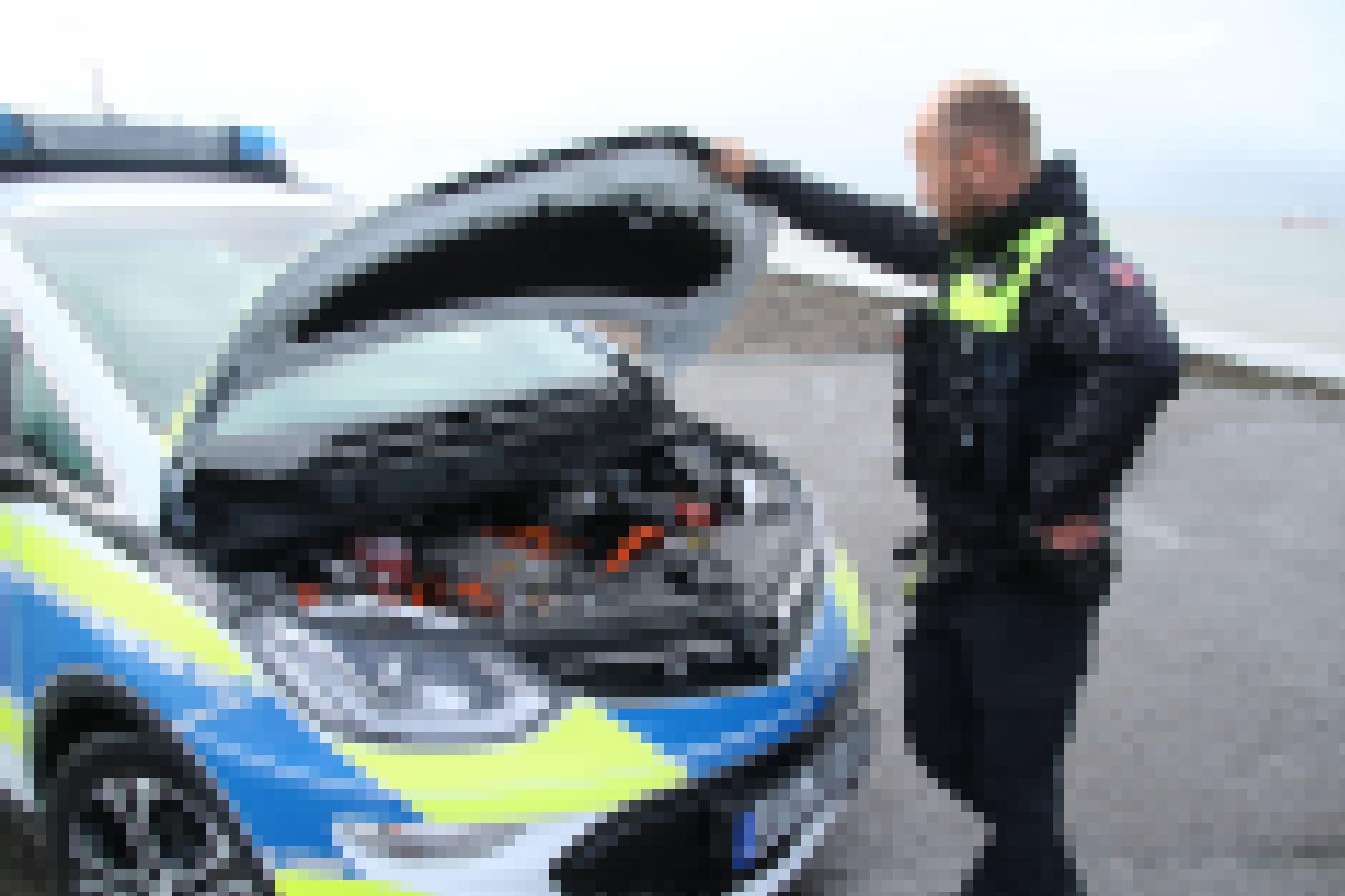 Polizist öffnet die Motorhaube seines Dienstfahrzeugs