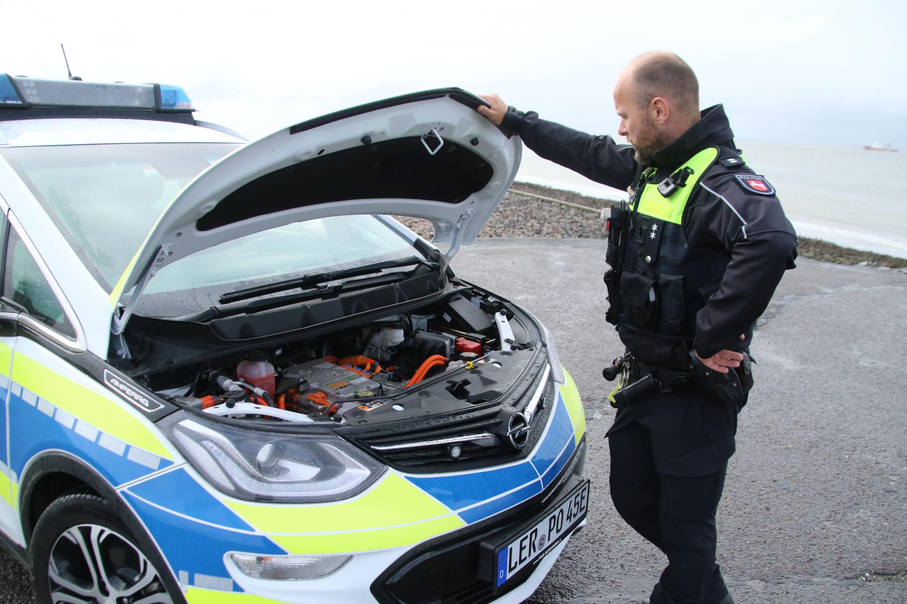 Polizist öffnet die Motorhaube seines Dienstfahrzeugs