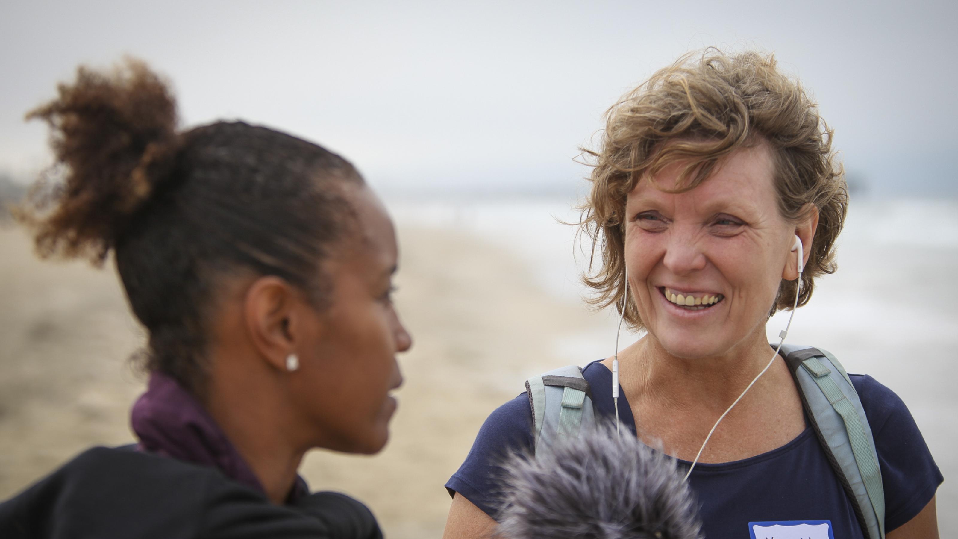 Eine afroamerikanische Frau wird von einer weißen Reporterin interviewt. Im Hintergrund der Pazifik, zwischen ihnen ein Mikrofon.
