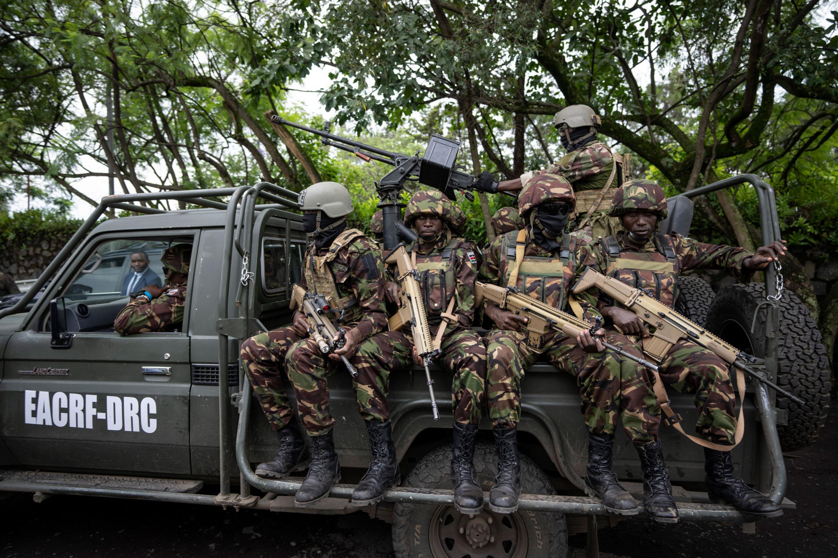 Ein militärischer Pickup mit Soldaten, die schwerbewaffnet hinten auf dem Pickup sitzen, in Tarnuniform und mit Helmen.