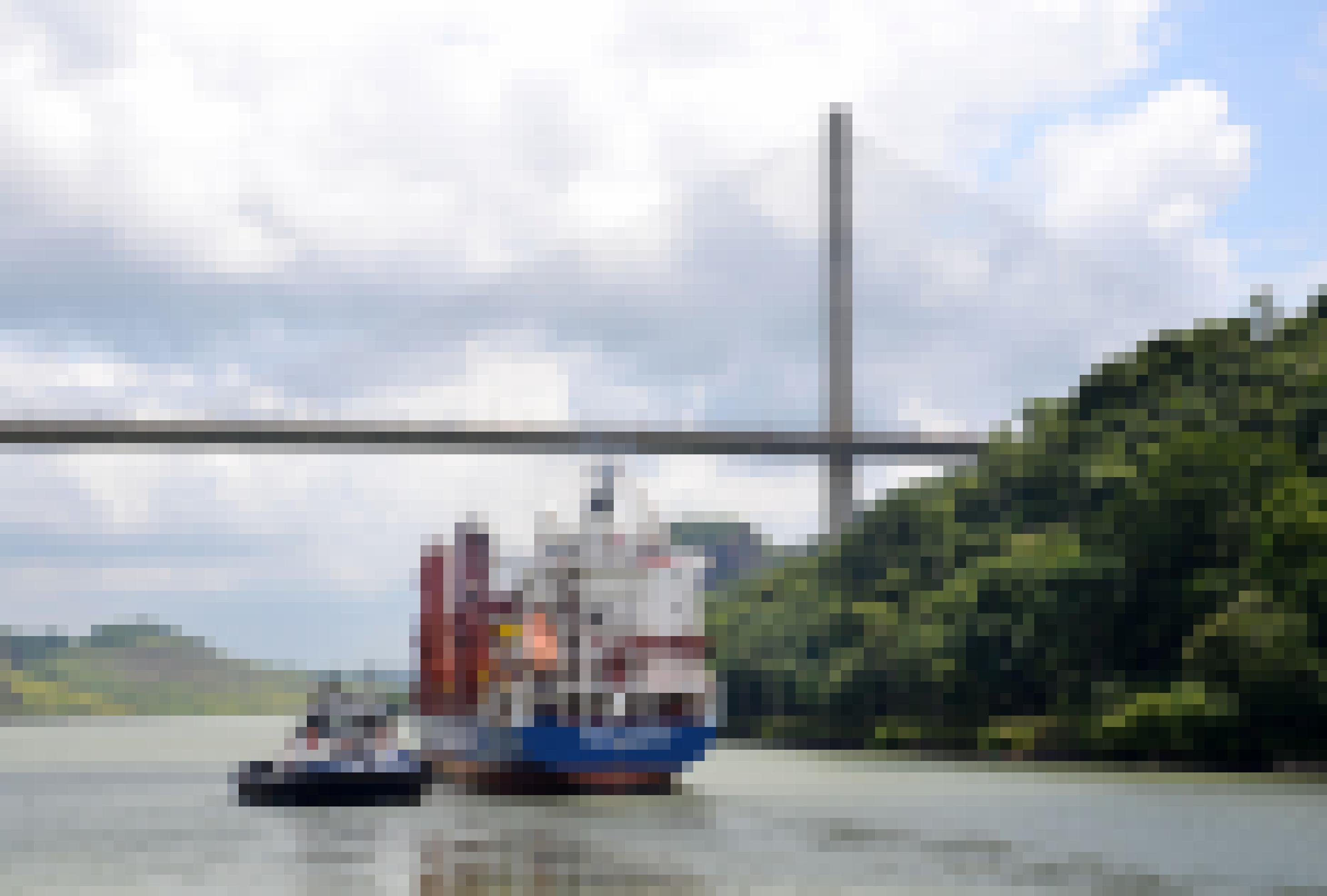 Beladenes Frachtschiff mit Begleit-Lotsenschiff vor einer Hängebrücke.