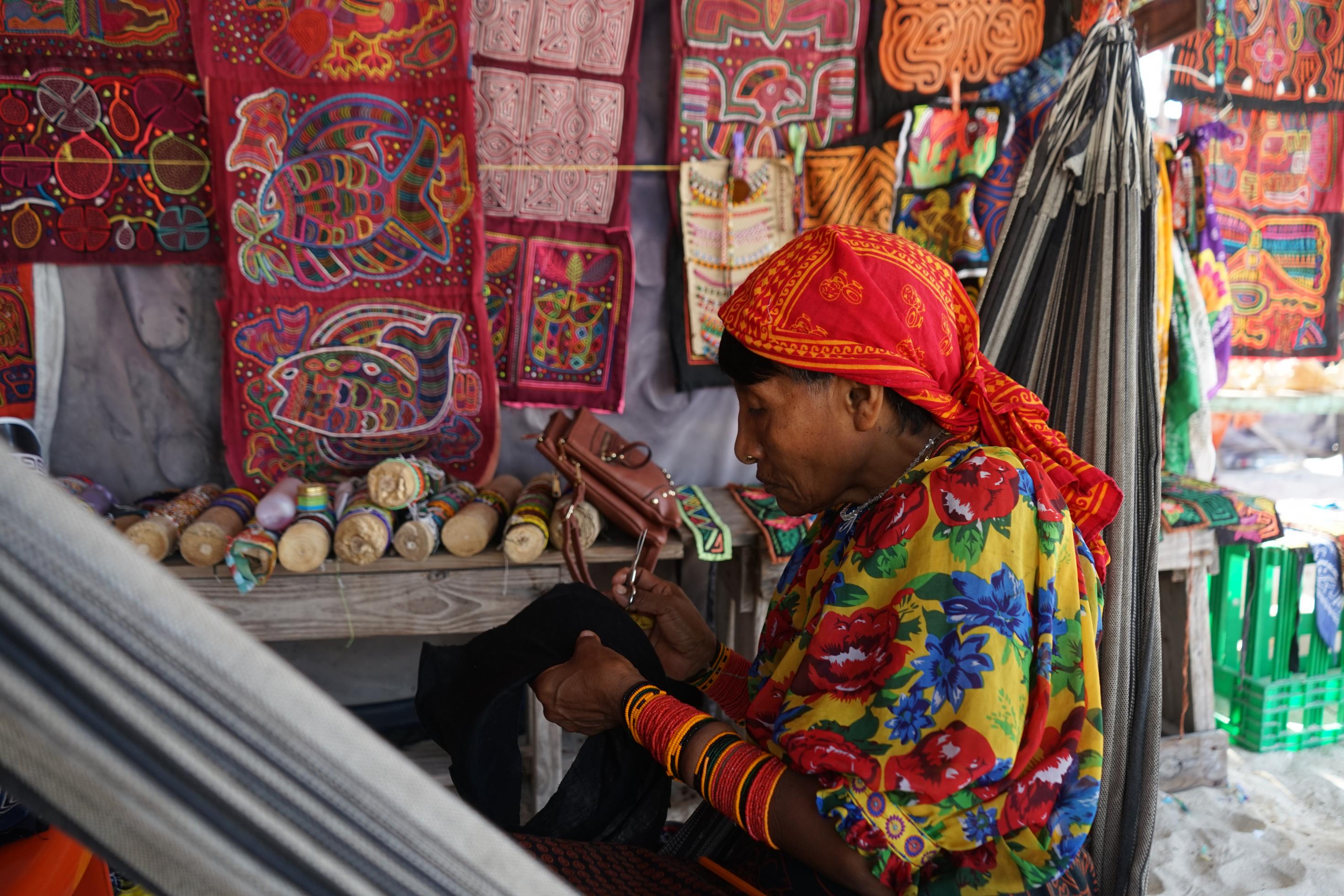 Eine Kuna-Indigene in traditioneller Tracht webt textiles Kunsthandwerk.