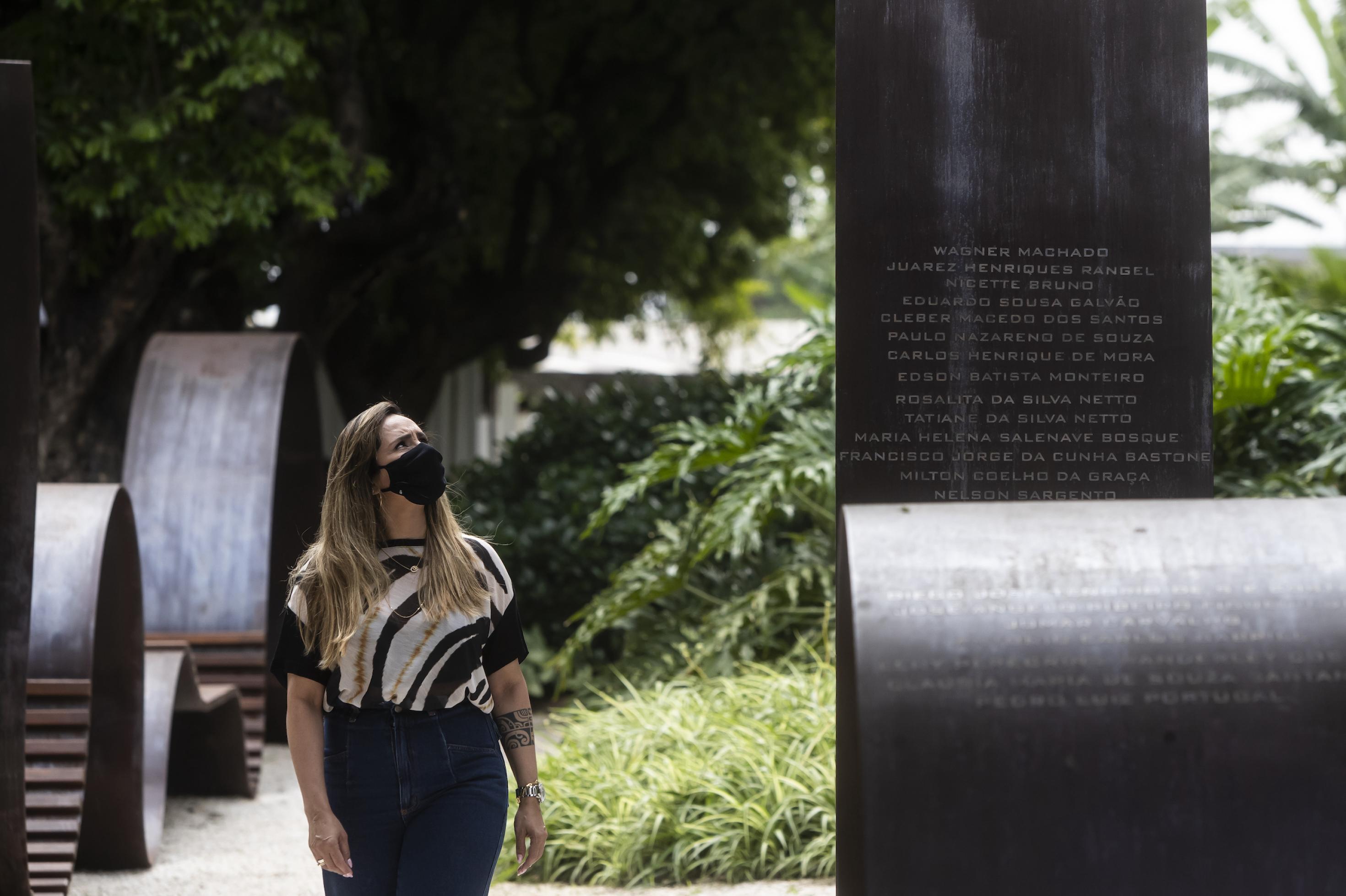 Eine Frau steht neben der Corona-Gedenkstätte – lange metallische Banden mit den Namen von Verstorbenen.