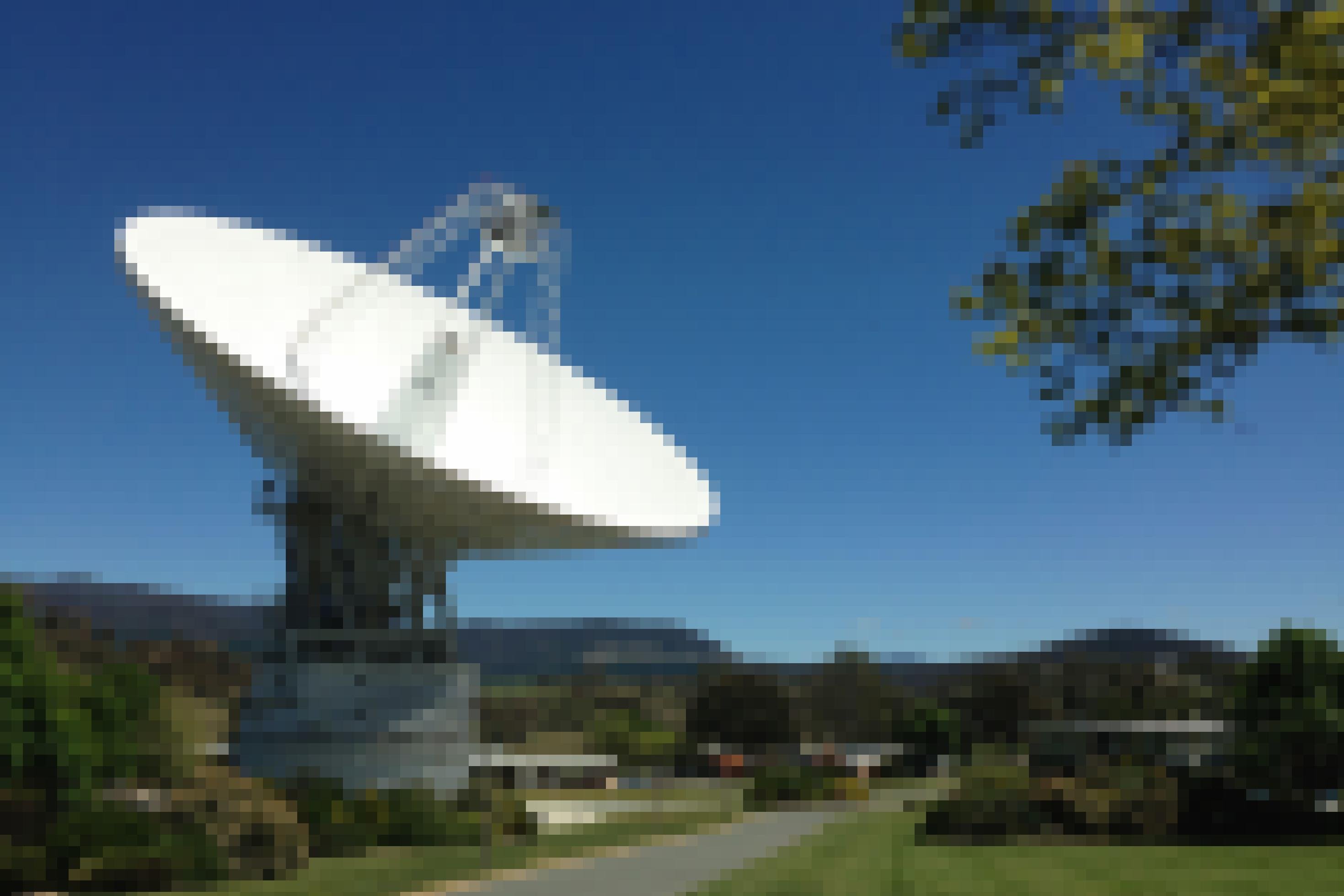 In sonnenbeschienener Landschaft ist die riesige Parabolantenne eines Radioteleskops in den Himmel gerichtet.