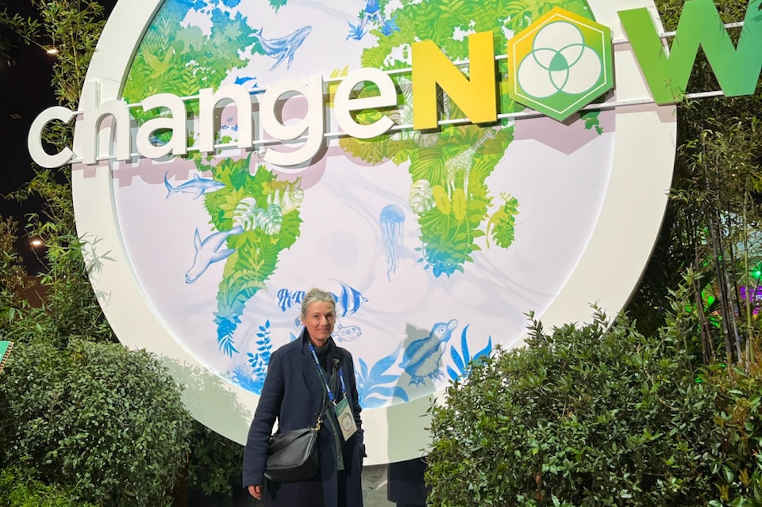 In Paris steht Weltreporterin Barbara Markert vor einem Schild der „Change Now“, einem Event mit Projekten zum Klimawandel.