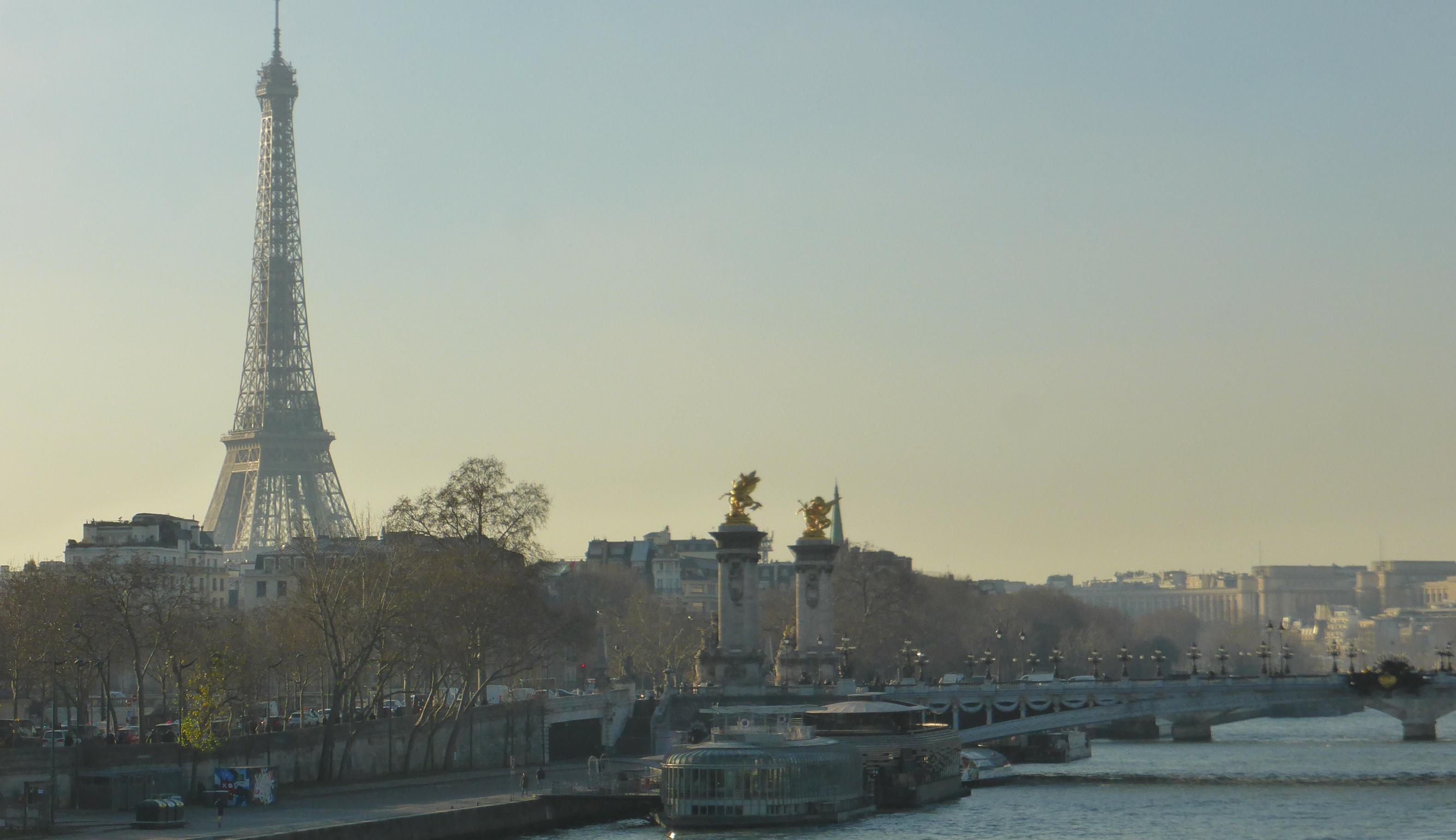 Neobarocker Brückenkopf mit goldglänzenden Statuen, dahinter bis an den oberen Bildrand ragend: der Eiffelturm.