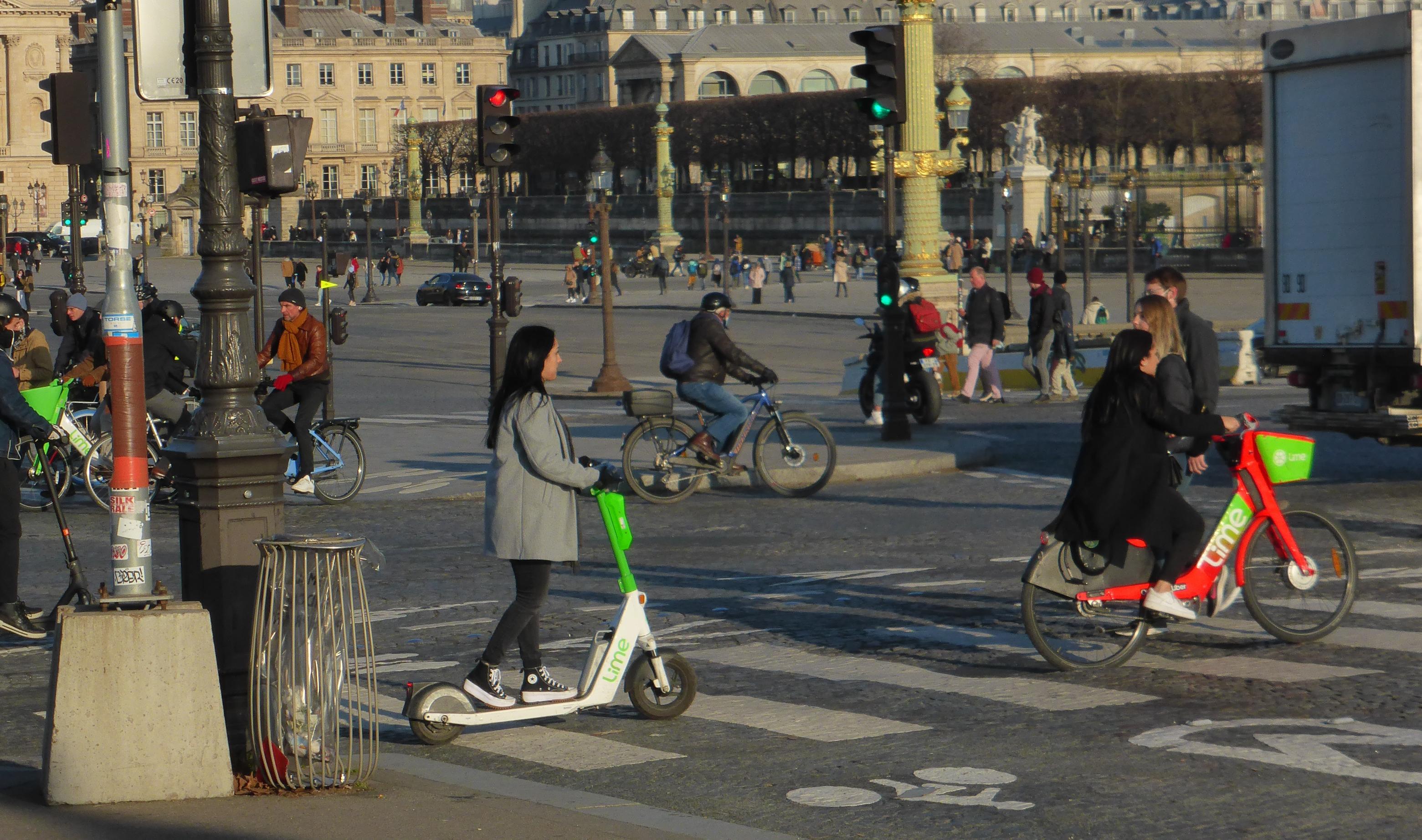 Straßenszene im Sonnenlicht, auf der reger Fahrrad- und Roller-Verkehr herrscht.