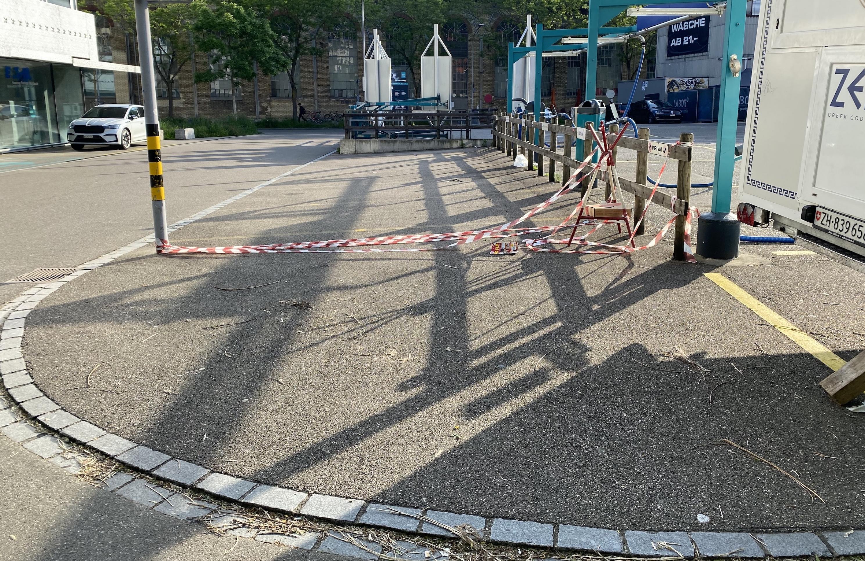 Rotweißes Flatterband trennt die asphaltierte Fläche zum Parken von der asphaltierten Restfläche.