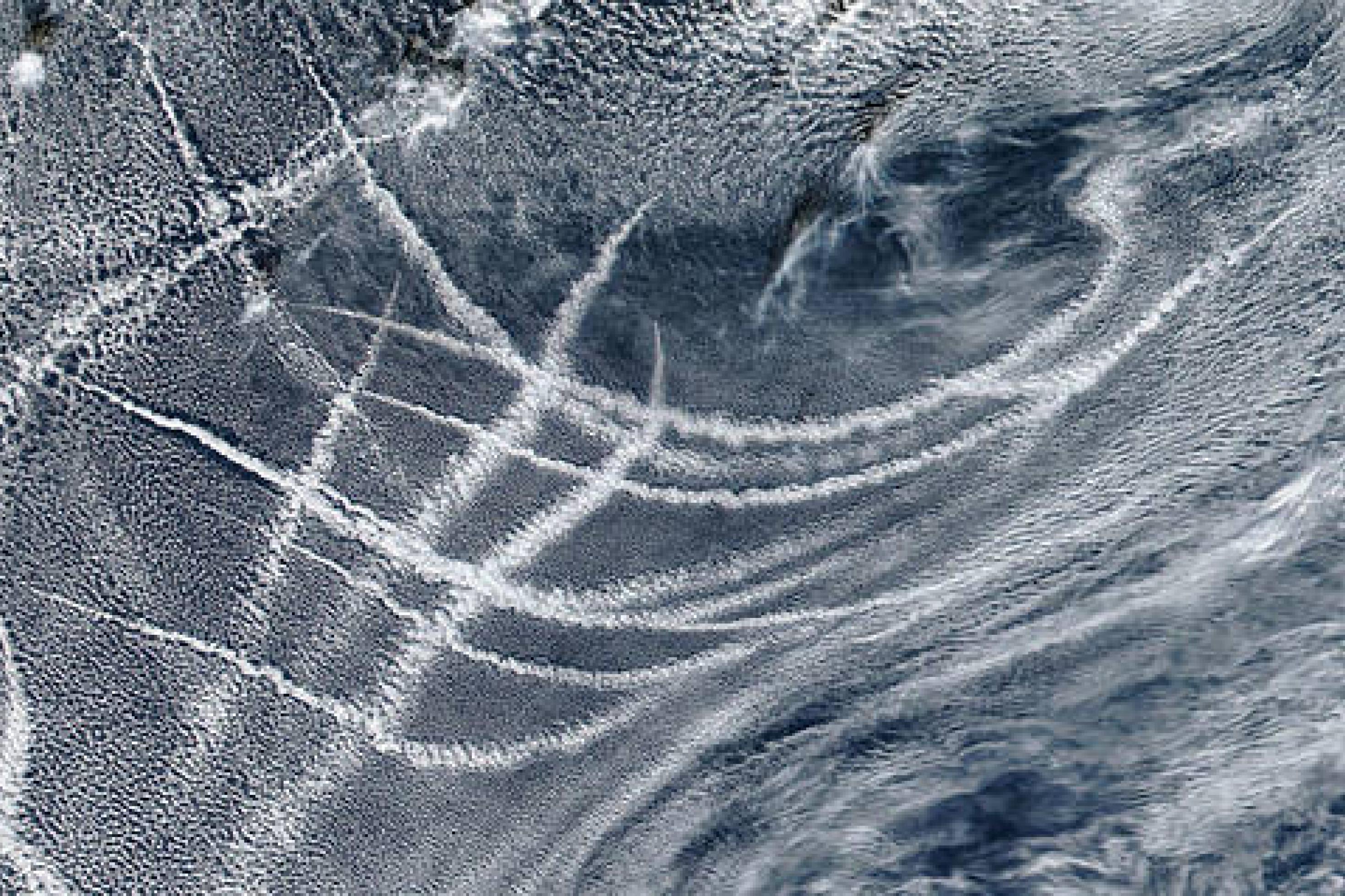 Eine Satellitenaufnahme der NASA vom Pazifik, die die Wolkendecke zeigt, durch die sich helle Kondensstreifen ziehen, die durch Schiffsabgase gebildet werden.