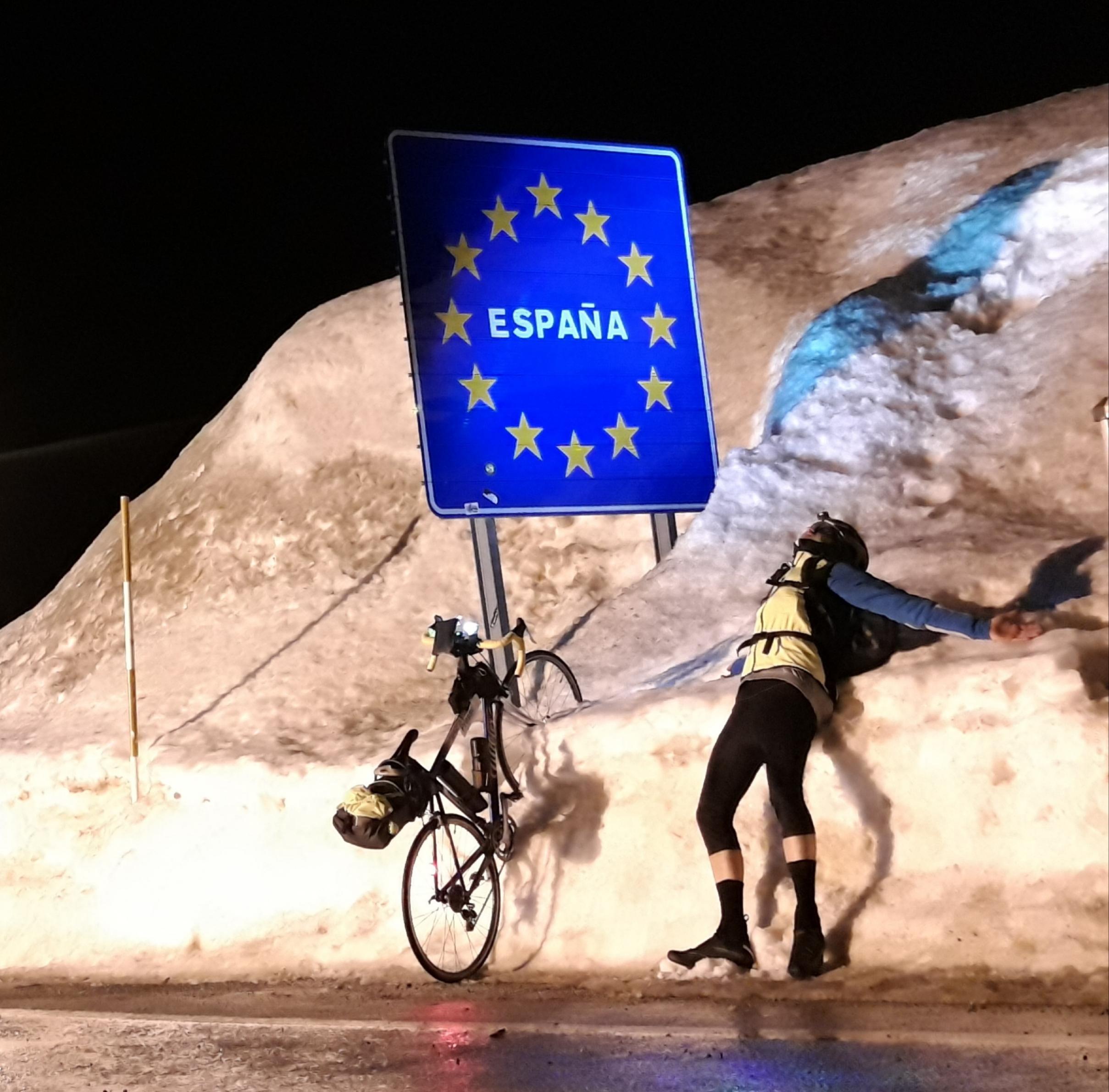 Der Reporter hat das Vorderrad seines Vehikels in den meterhohen Schnee am Straßenrand gesteckt, aus dem das EU-Landesgrenzen-Schild von Spanien herausragt. Er selbst liegt, den Kopf in den Schnee gedrückt, rücklings vor dem Grenzschild.