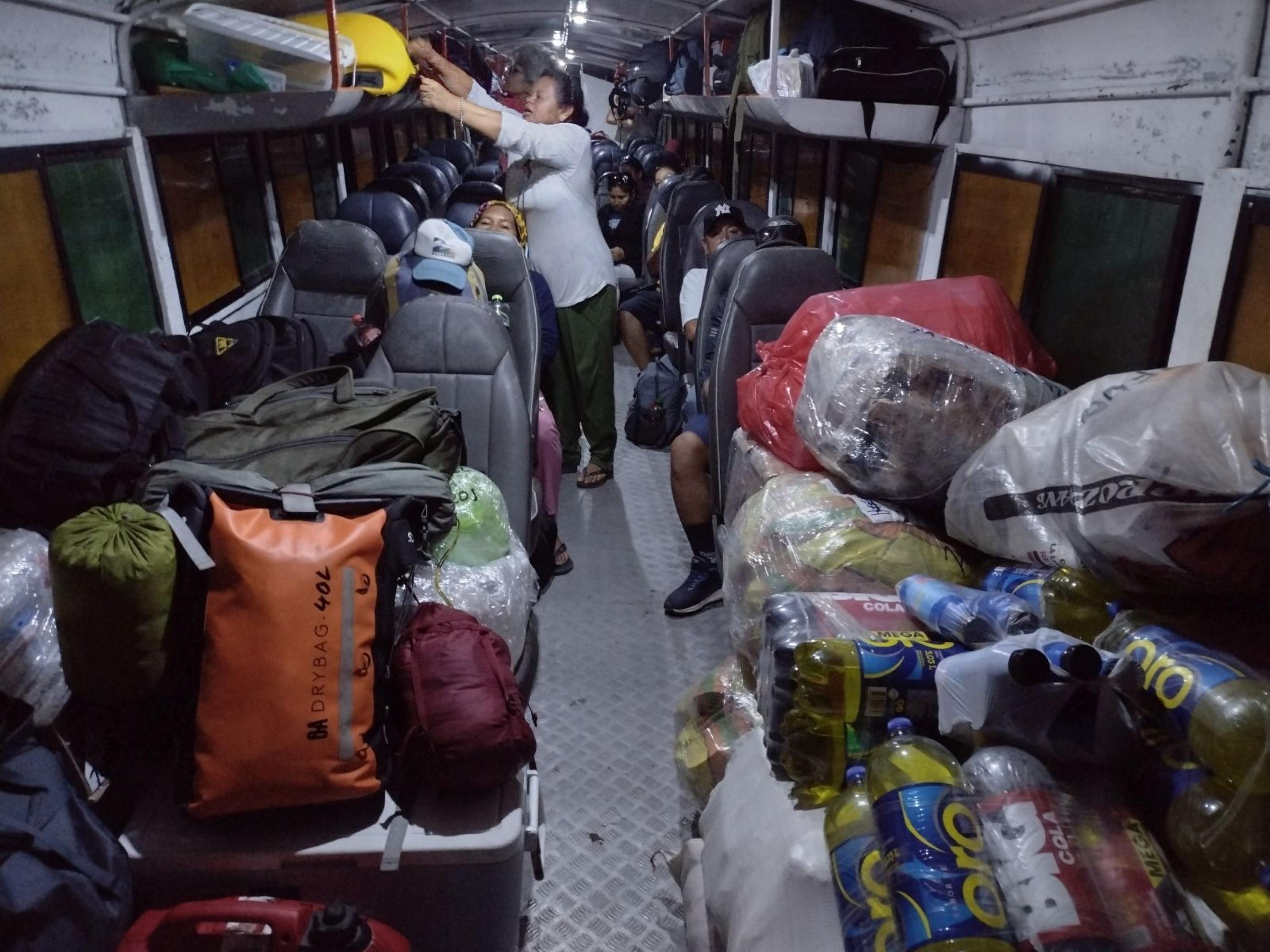Das Innere eines Motorboots mit Sitzen wie in einem Bus. Passagiere verstauen ihr Gepäck und nehmen Platz.