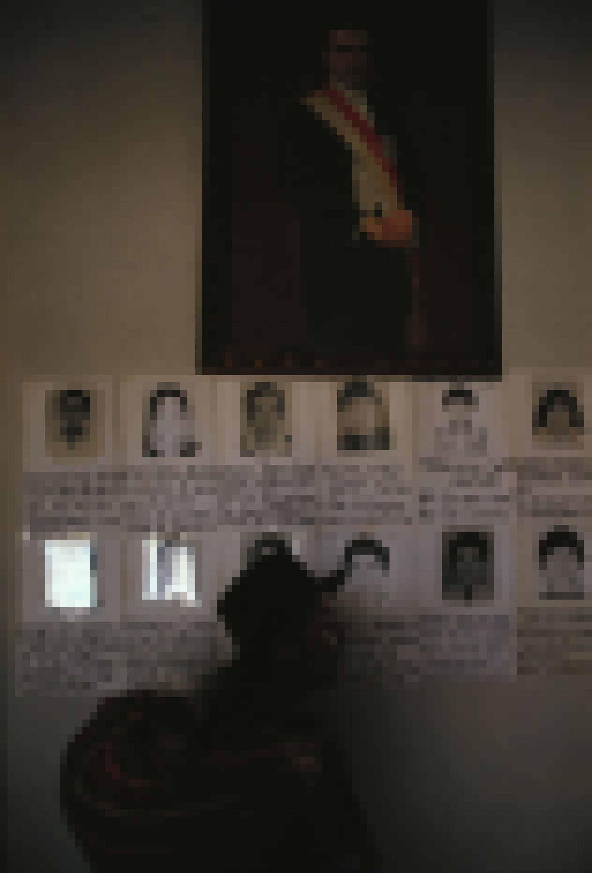 Ayacucho 1985. Obere Bildhälfte ist ein Gemälde eines Würdenträgers Perus. Darunter handgeschriebene Steckbriefe junger Männer mit Foto. Davor geht schemenhaft eine indigene Frau mit Hut und einem Stoffbündel auf dem  Rücken vorbei.
