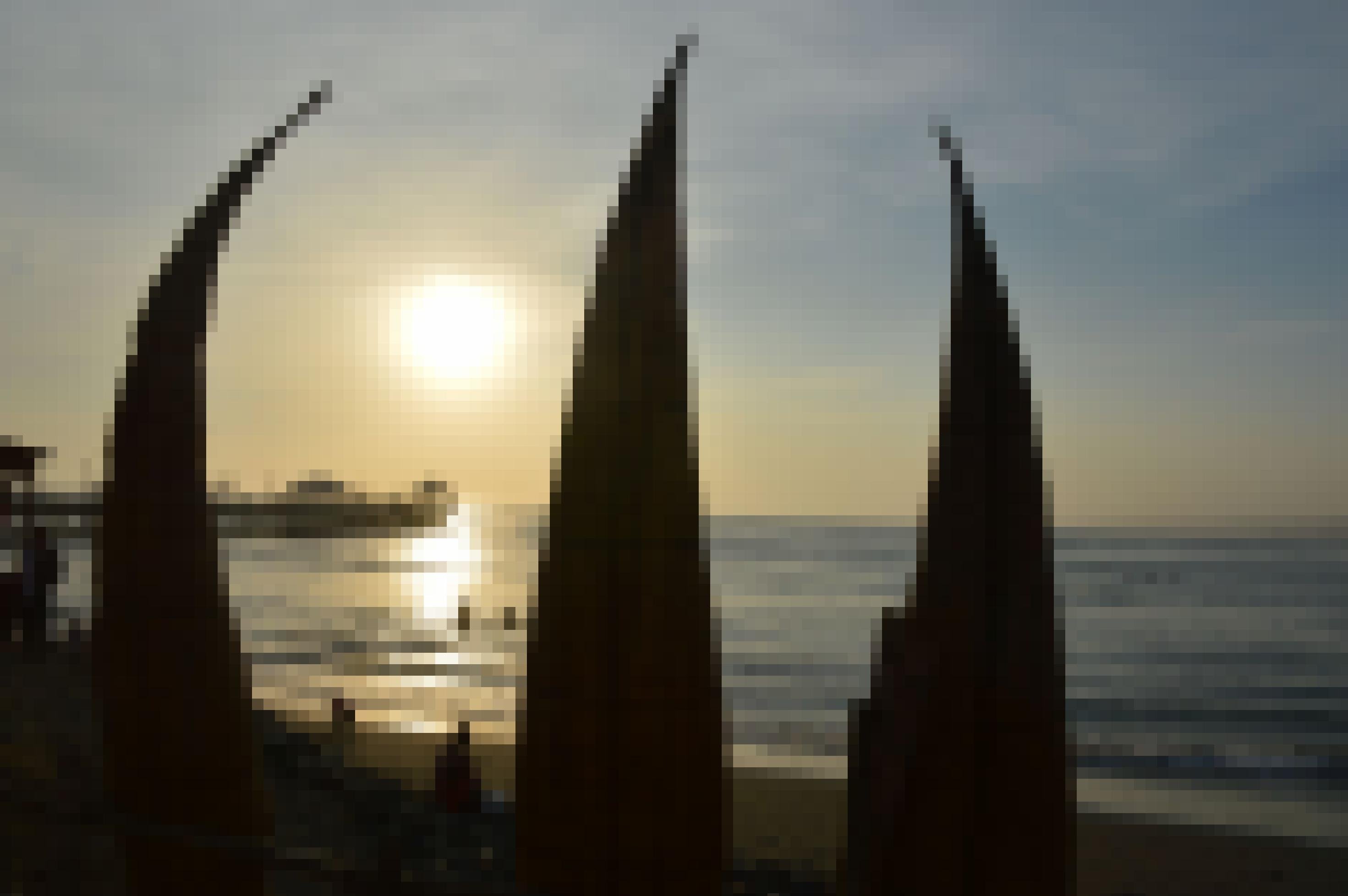 Aufgestellte Schilfboote am Strand vor dem Pazifik, im Hintergrund Sonnenuntergang