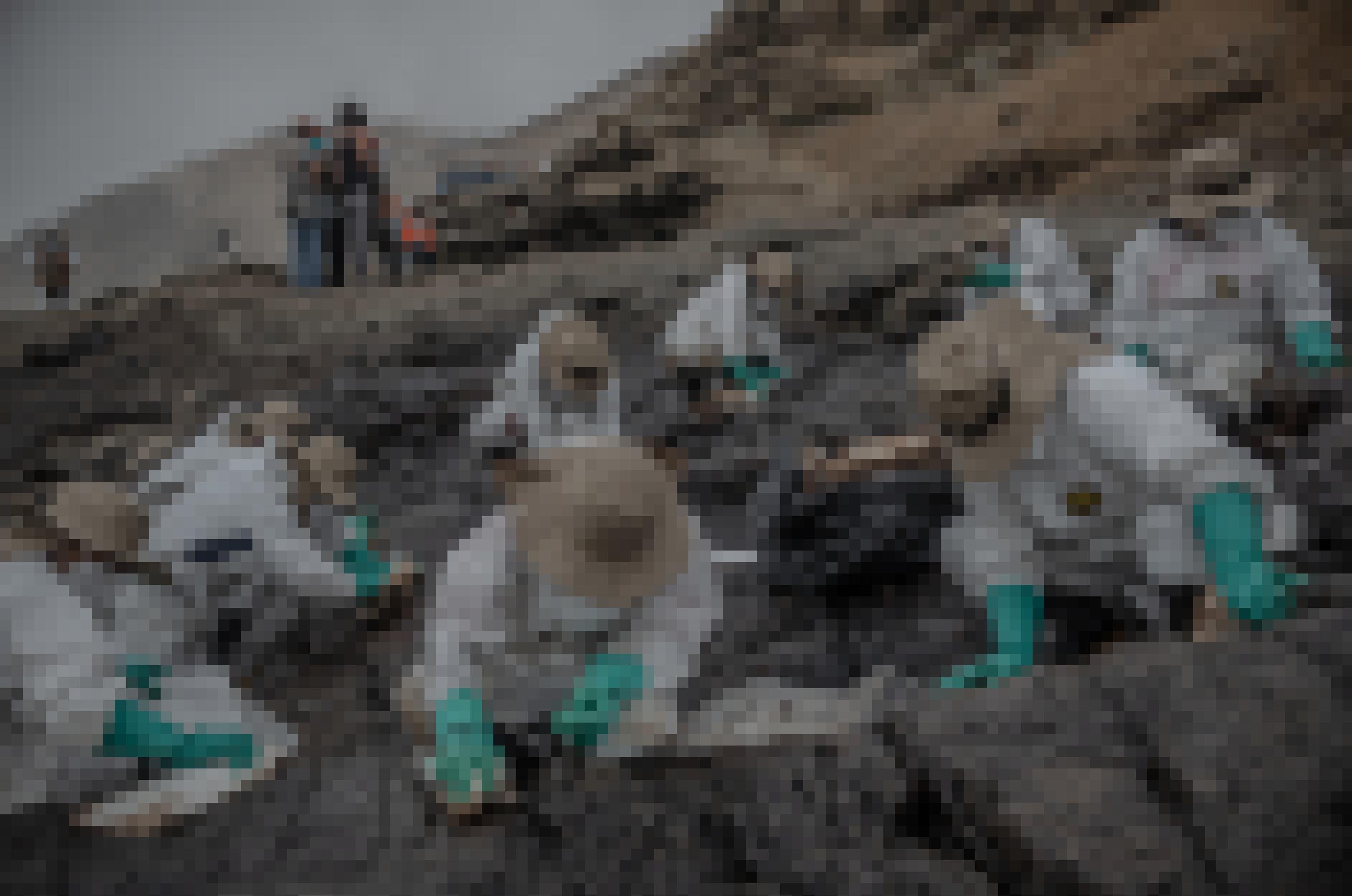 Felsen am Meer, darauf sitzen neun Frauen mit weissen Anzügen, Rangerhüten und Stoffmaske und wischen mit weissen Tüchern das Erdöl ab.