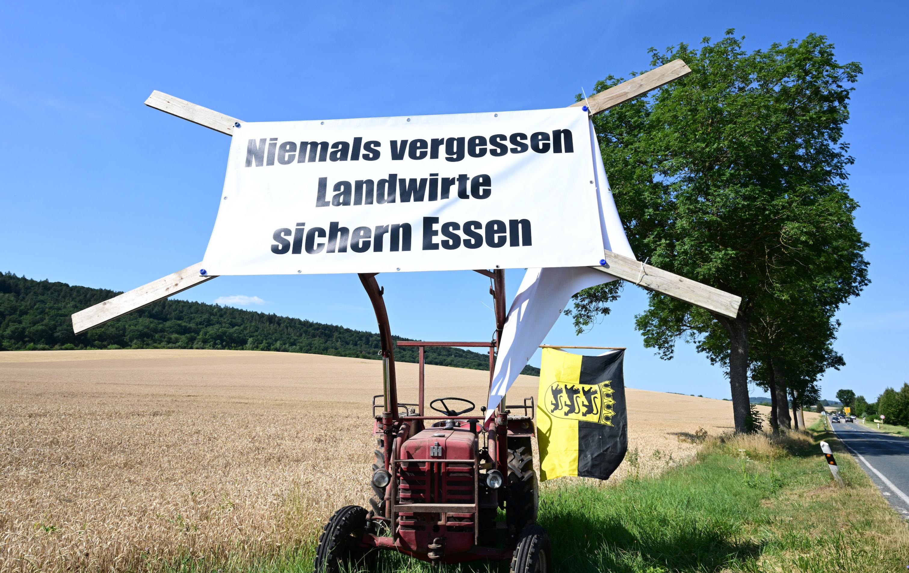 Ein Traktor steht am Straßenrand mit einem Plakat „Niemals vergessen, Landwirte sichern Essen“