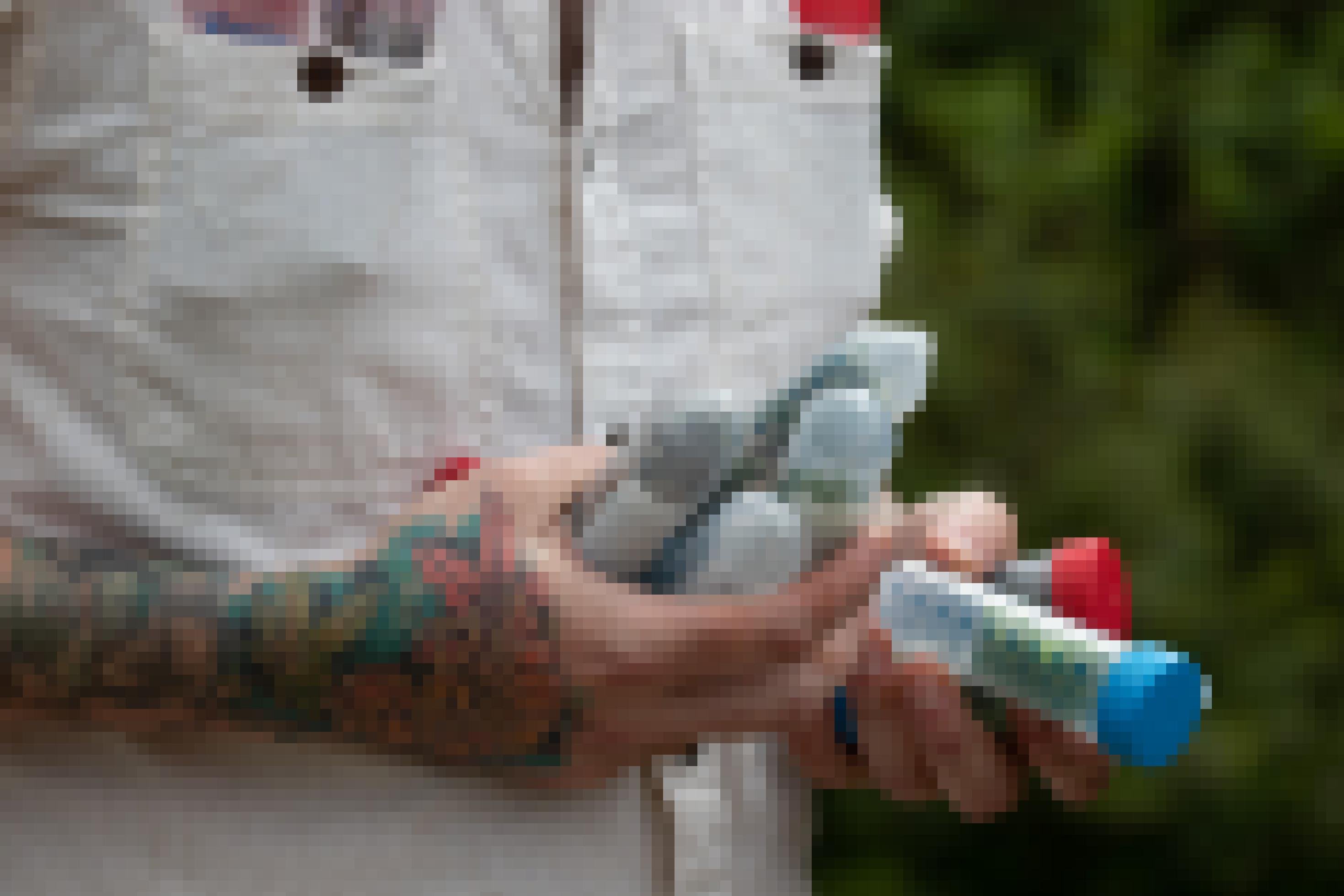 Mann mit tätowiertem Arm hält Kunststoffröhrchen mit Proben in der Hand.