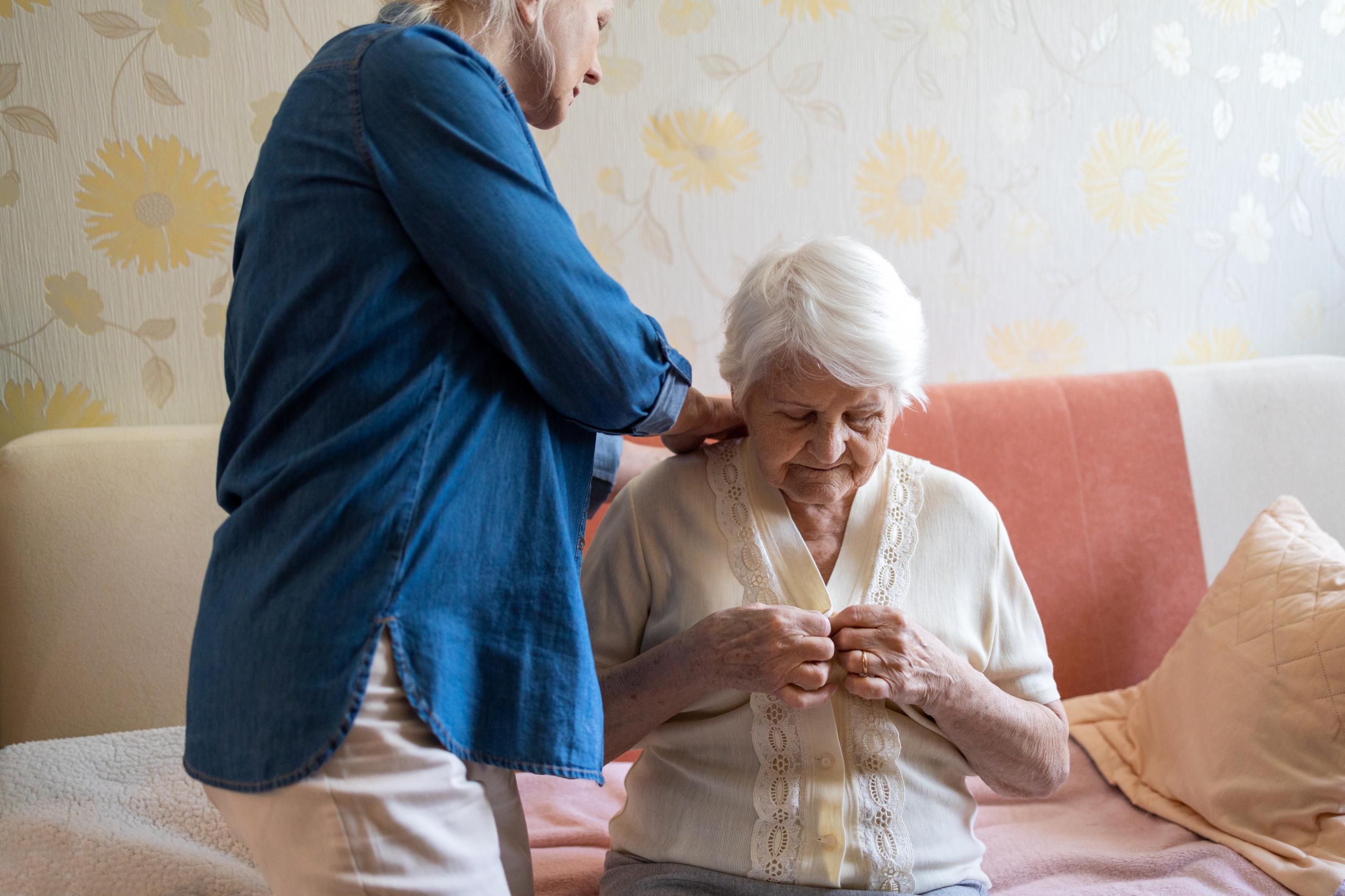 Eine Pflegekraft hilft einer alten Frau beim Ankleiden. Solche professionelle Unterstützung wird immer teurer. Die Pflegereform sieht aber nur leichte Erhöhungen der Pflegeleistungen vor.