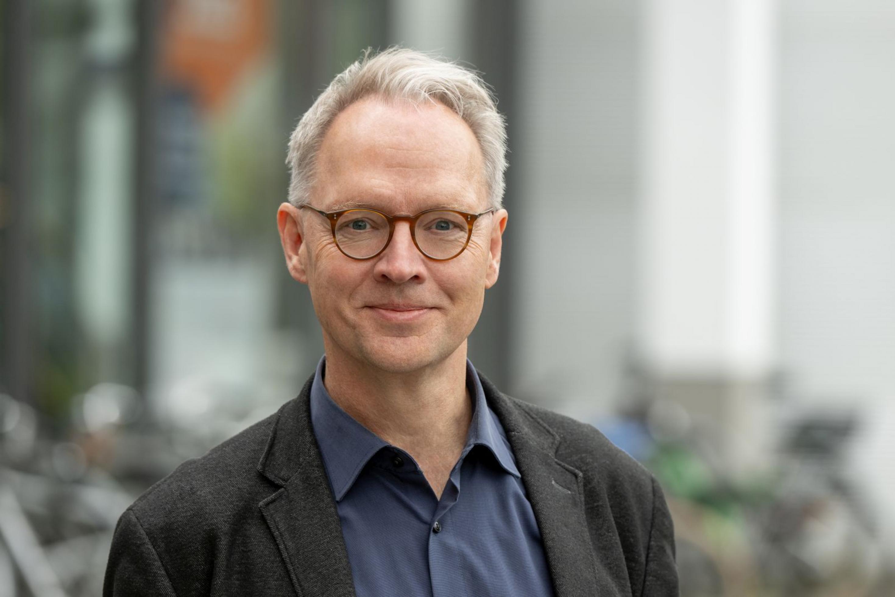 Brustbild eines rund 50-jährigen Mannes mit weissen Haaren und Brille.