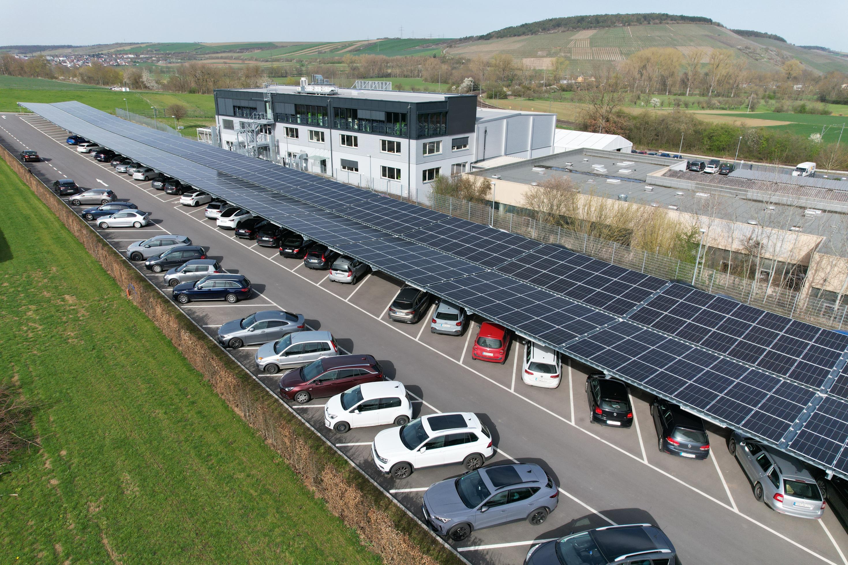 Luftbild eines Parkplatzes, der zum Teil mit Photovoltaik-Modulen überdacht ist
