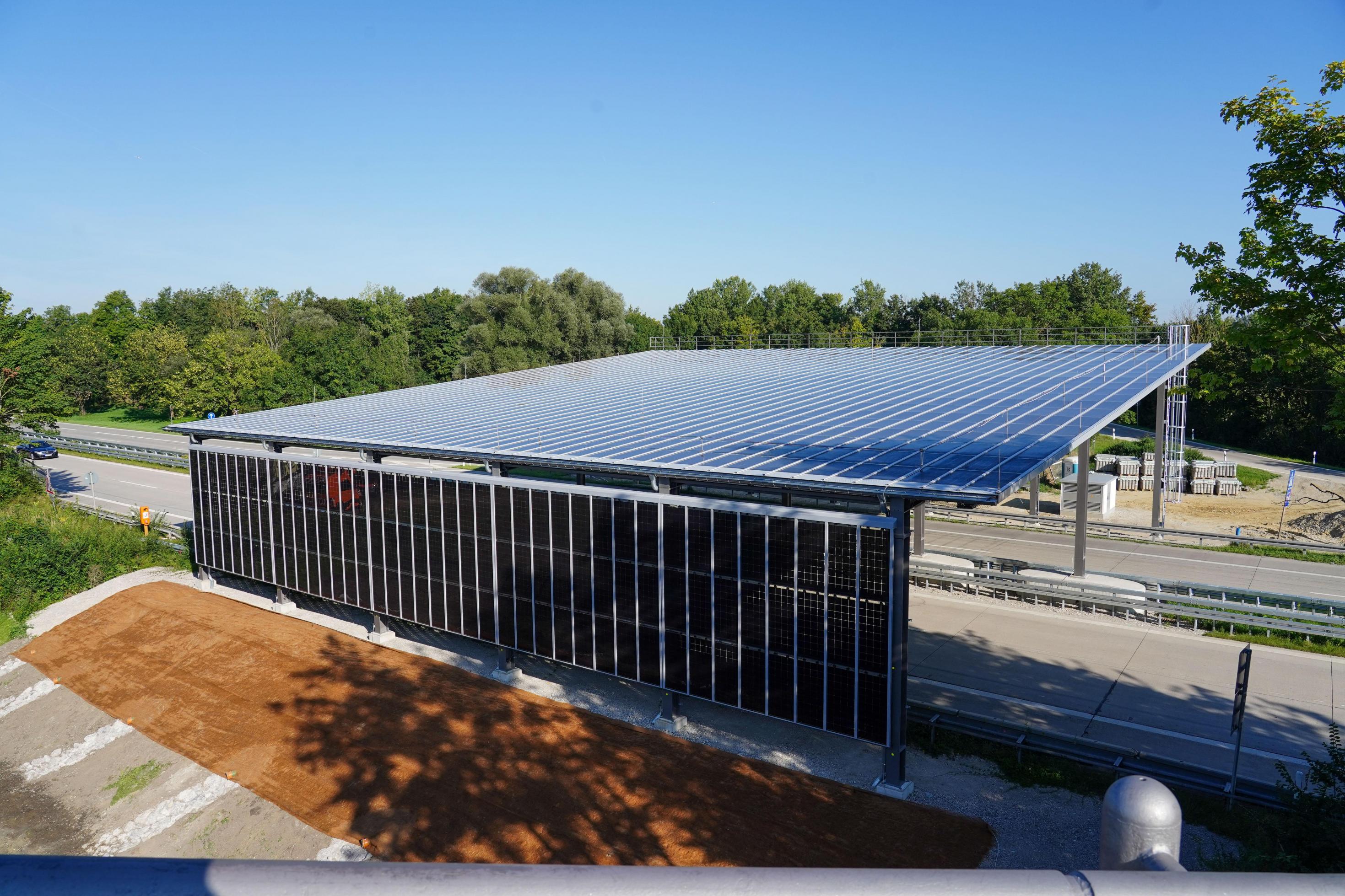 Hoch aufgeständerte Photovoltaik-Anlage über einer vierspurigen Straße aus der Vogelperspektive
