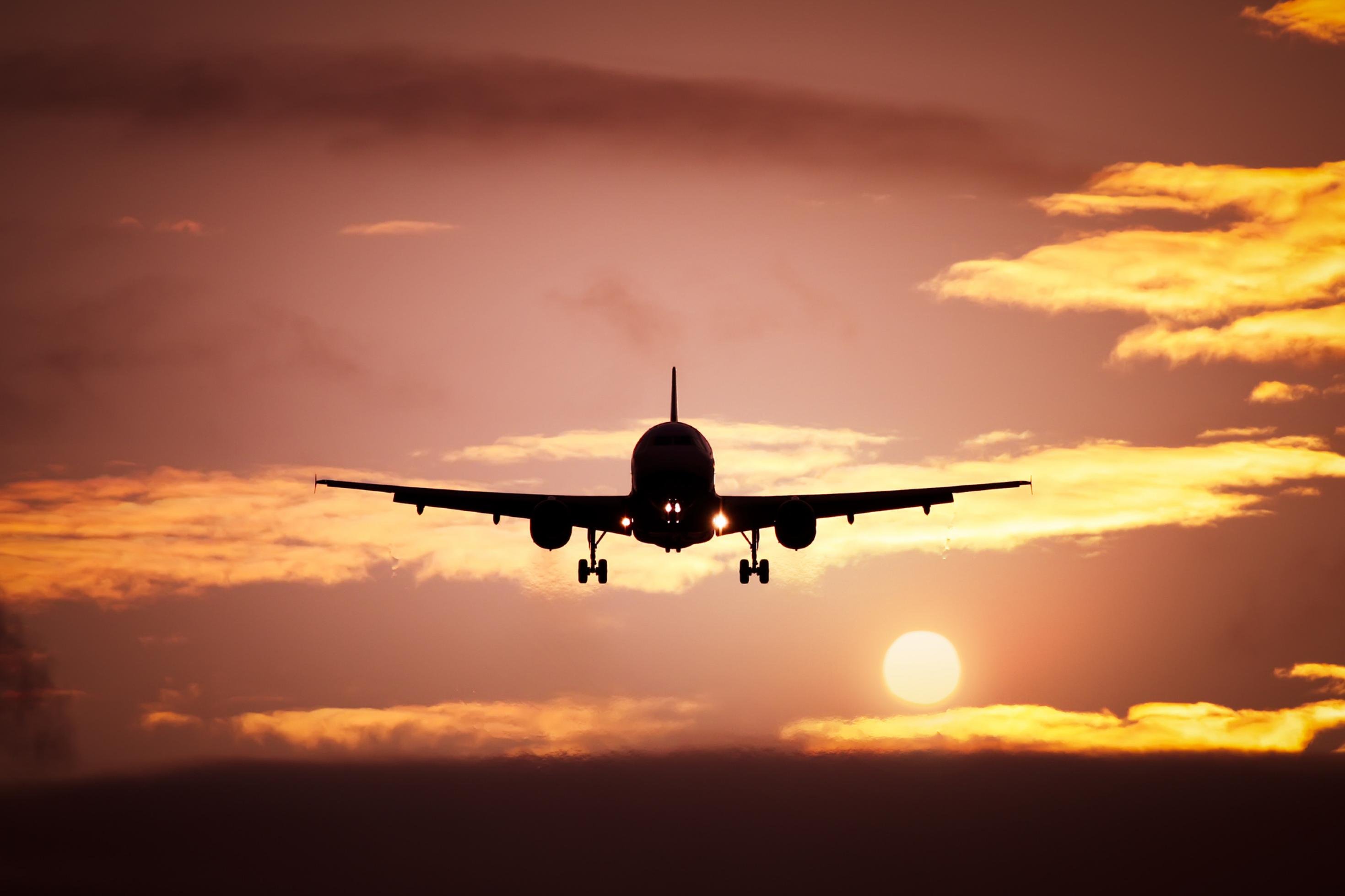 Ein Flugzeug im Start Richtung Sonnenuntergang.