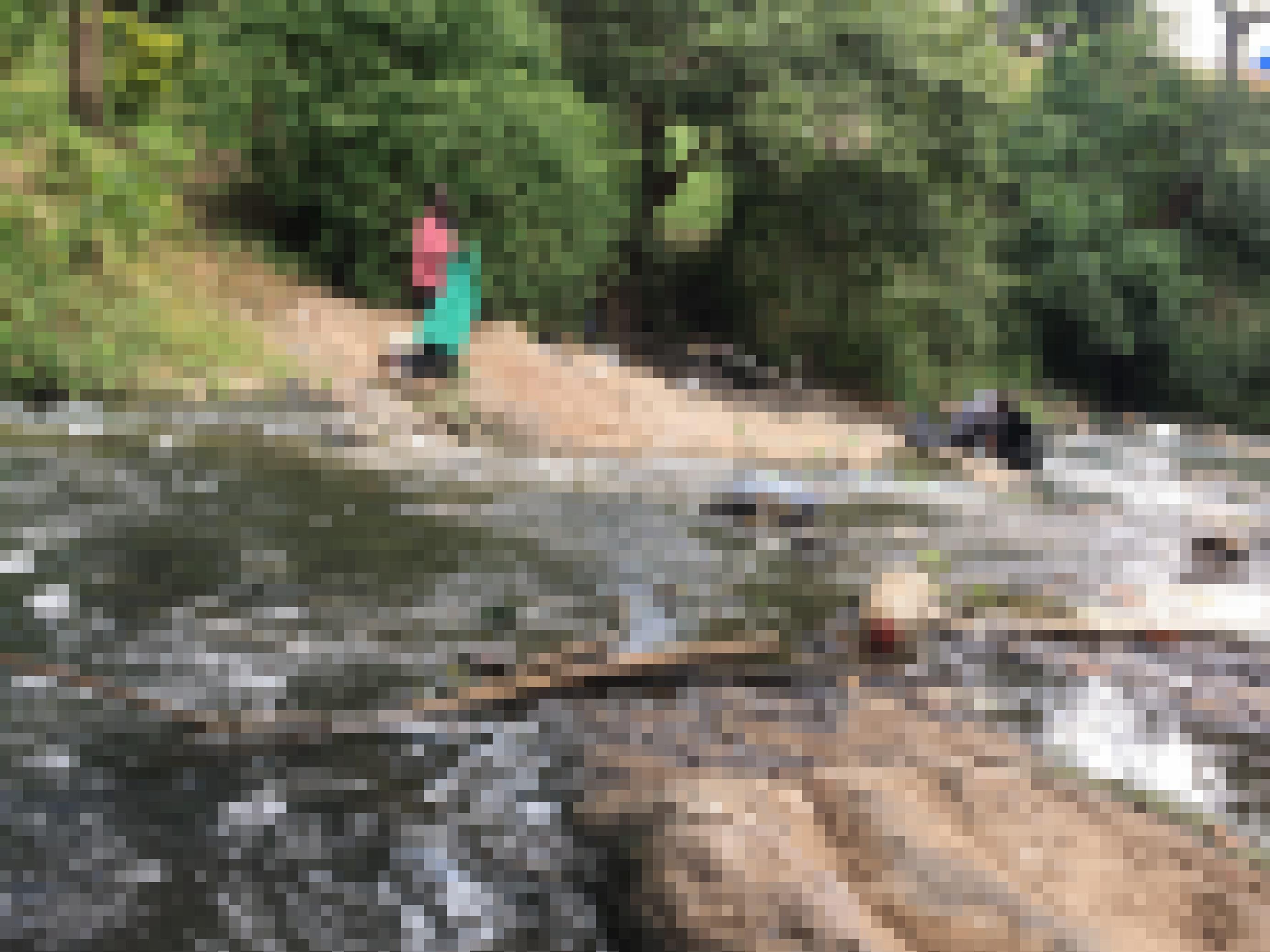 Zwei Männer an einem mit Plastikmüll verschmutzten Fluss in Malawi. Einer hat eine Mülltüte in der Hand, der andere sammelt den Abfall ein.