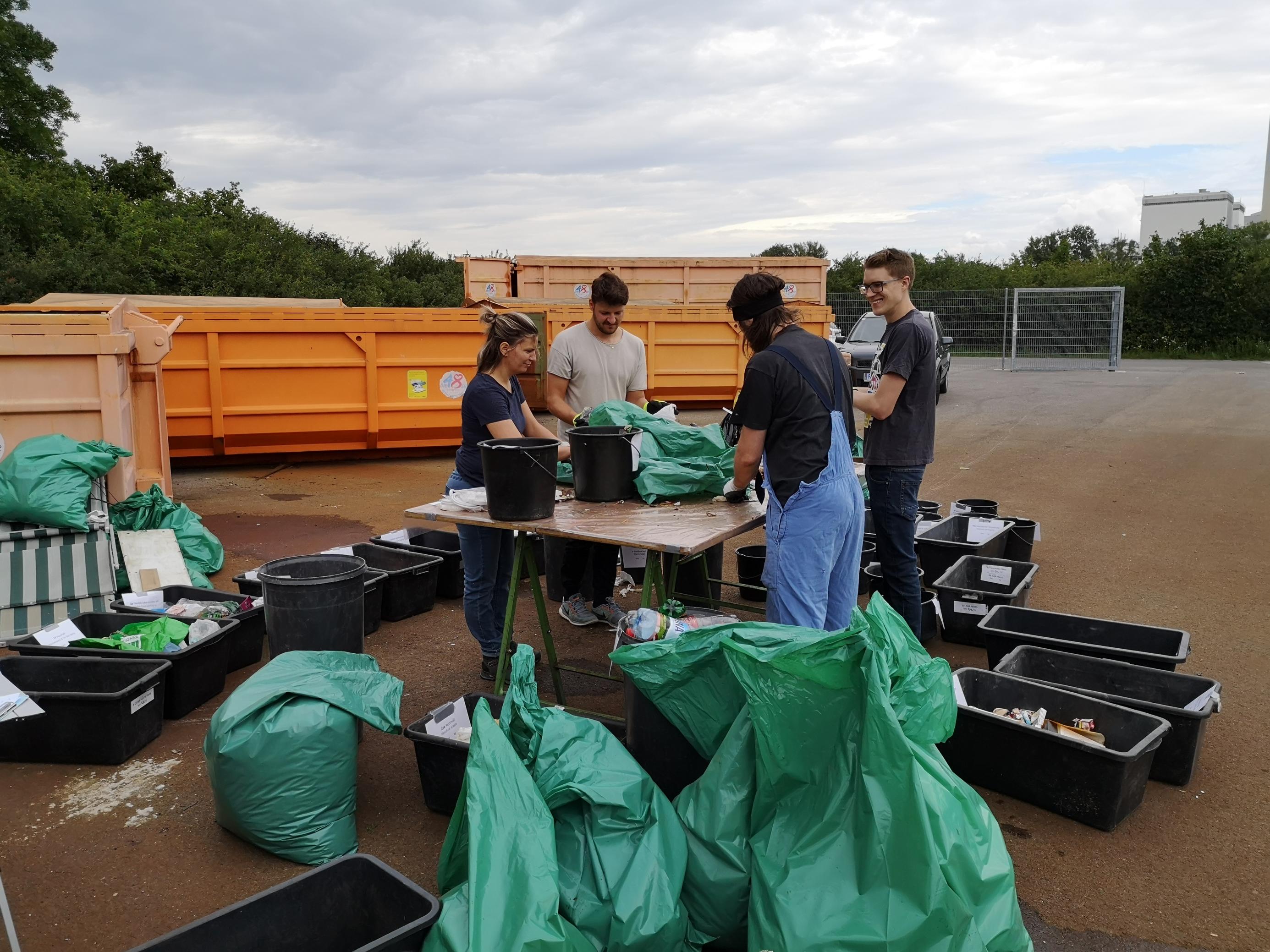 Forscherinnen und Forschern sortieren im Freien Plastikmüll in verschiedene Behälter.