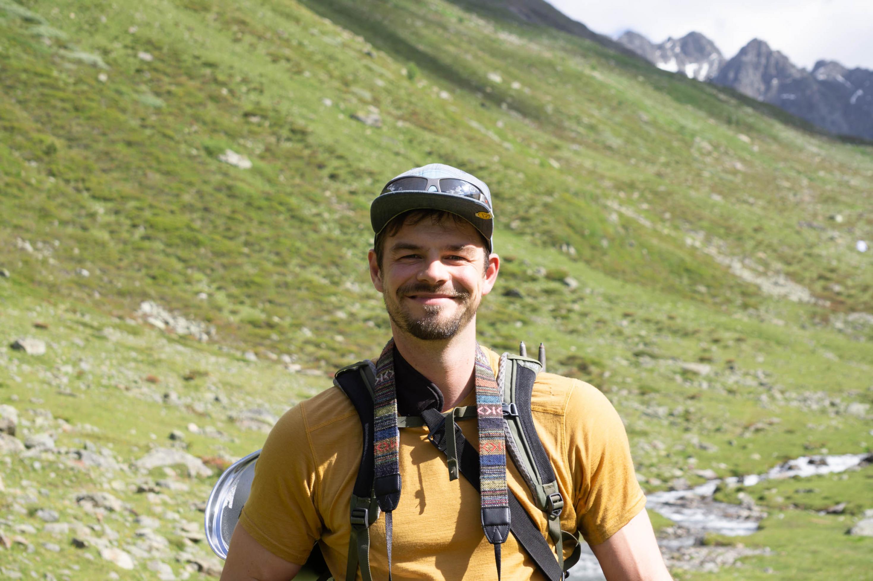 Junger Mann mit Rucksack in Alpental