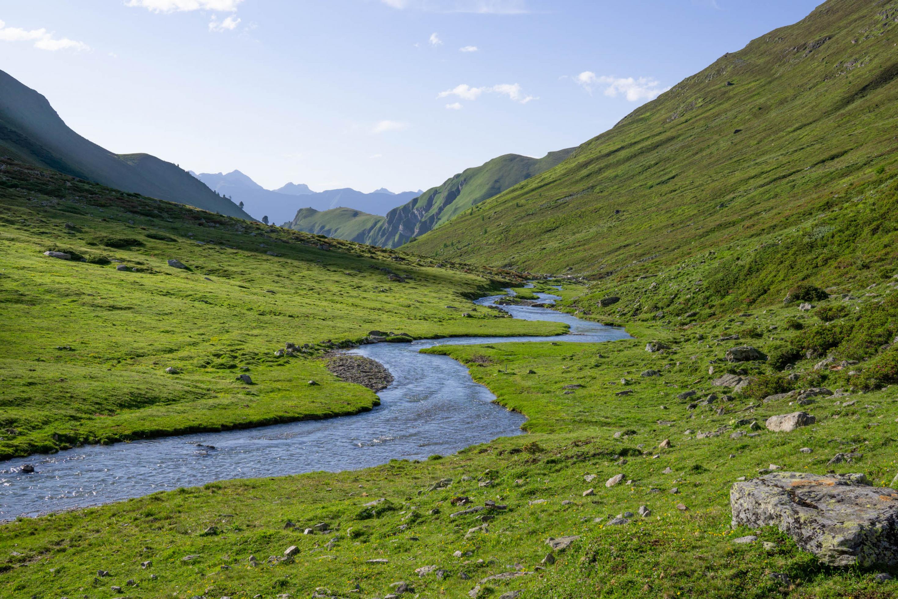 Weites Hochtal mit mäanderndem Bach