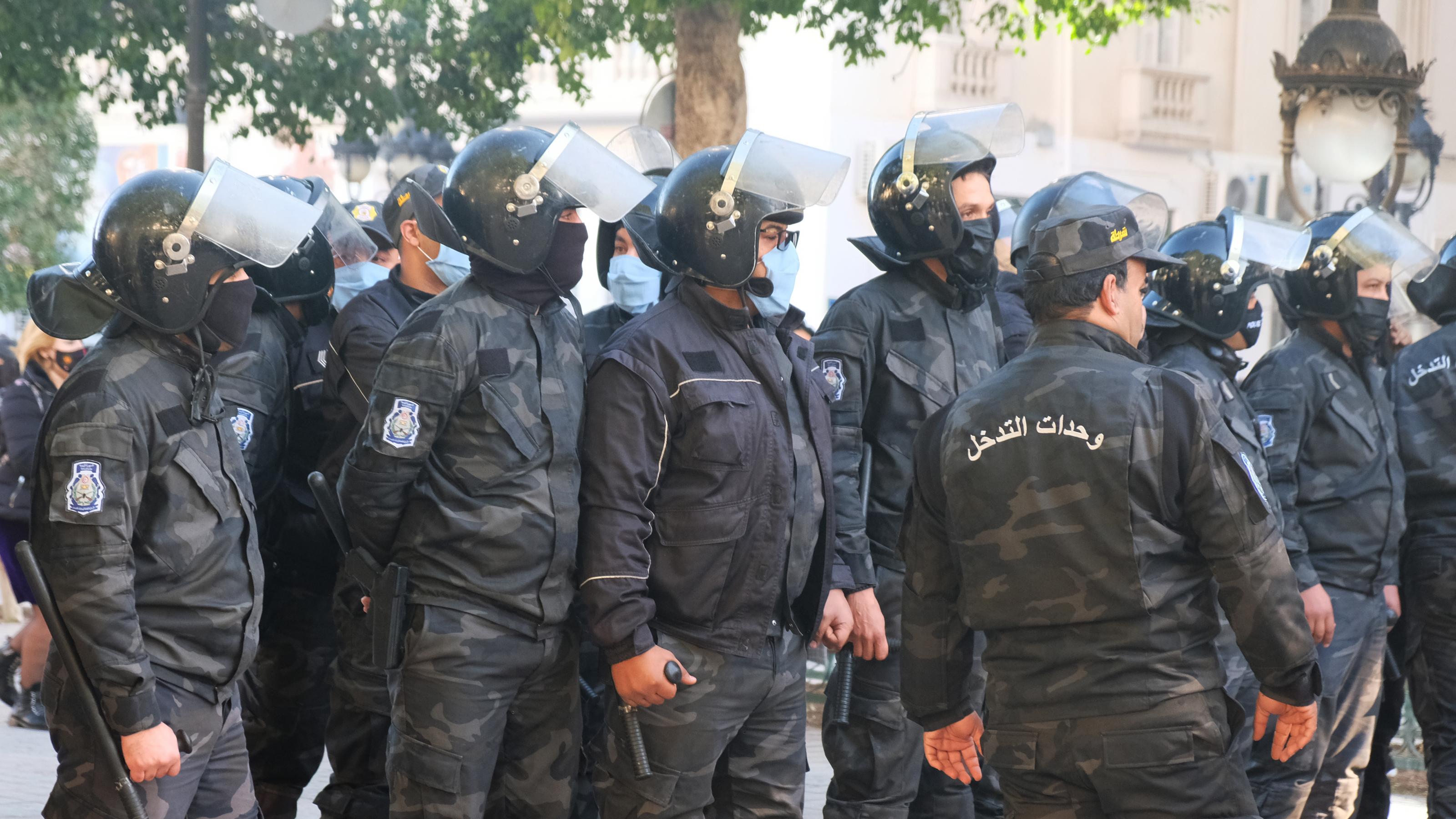 Reihe von Polizisten in schwarzer Uniformen mit Helmen, Schlagstöcken und Gesichtsmasken