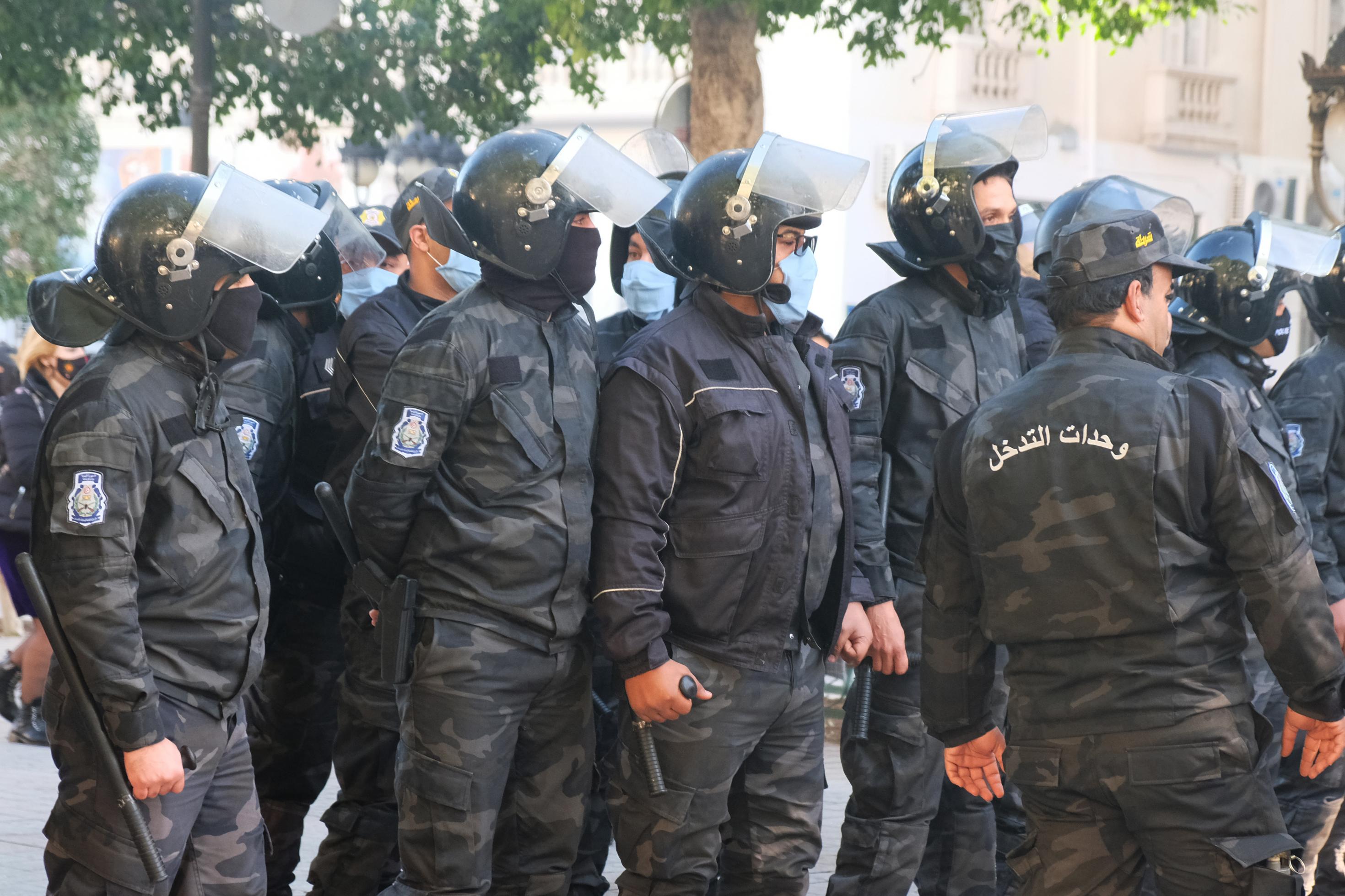 Reihe von Polizisten in schwarzer Uniformen mit Helmen, Schlagstöcken und Gesichtsmasken