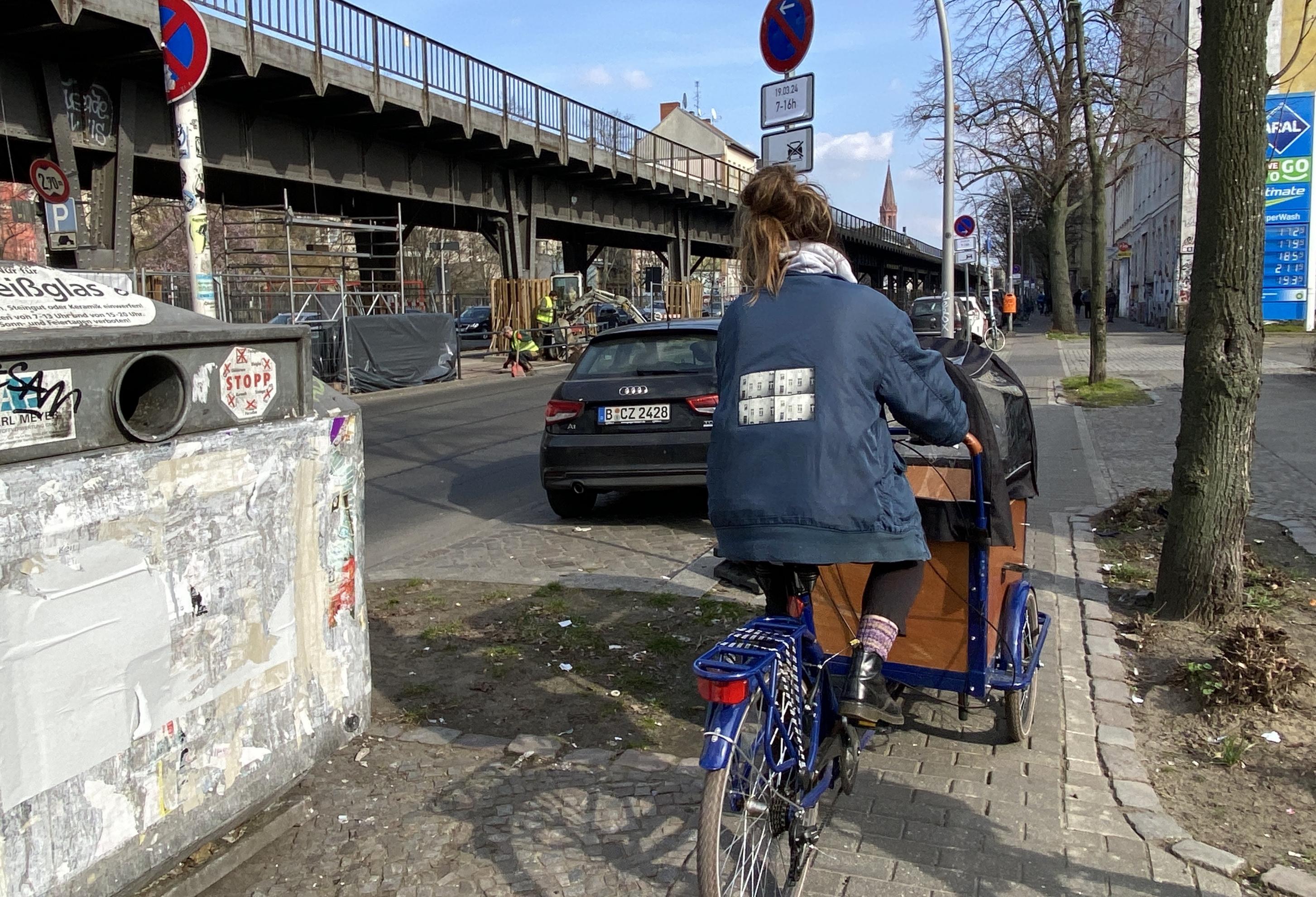 Ein Frau fährt mit dem Lastenrad auf eine Radweg