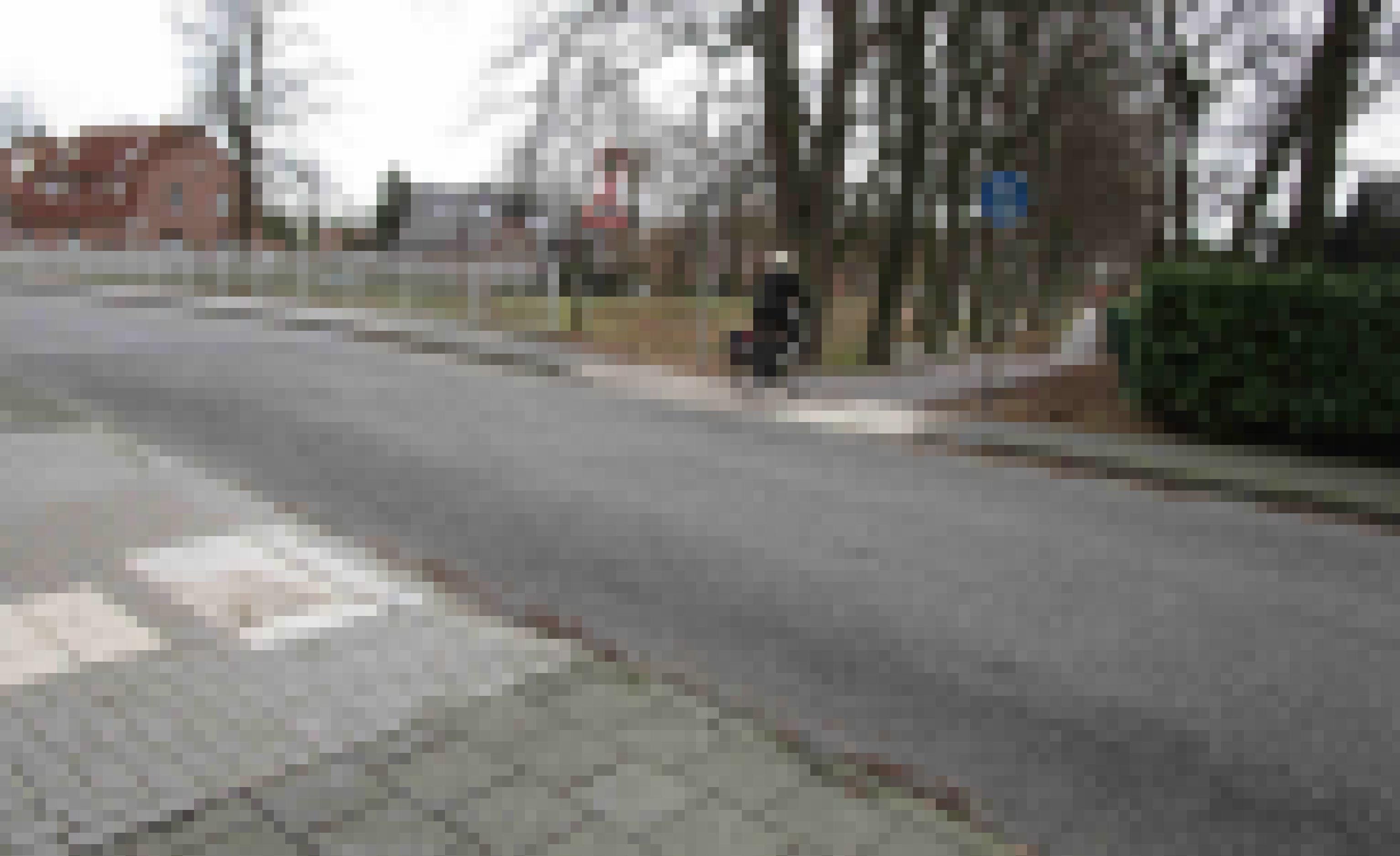 Eine Frau überquert mit ihrem Fahrrad eine Straße und biegt auf einen Rad- und Fußweg ab