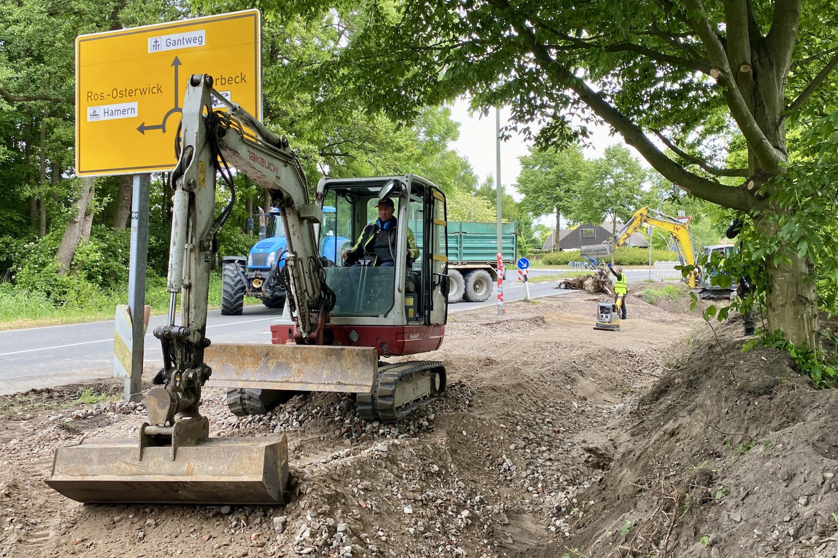 Baustelle: Bagger verteilen Schotter neben einer Straße