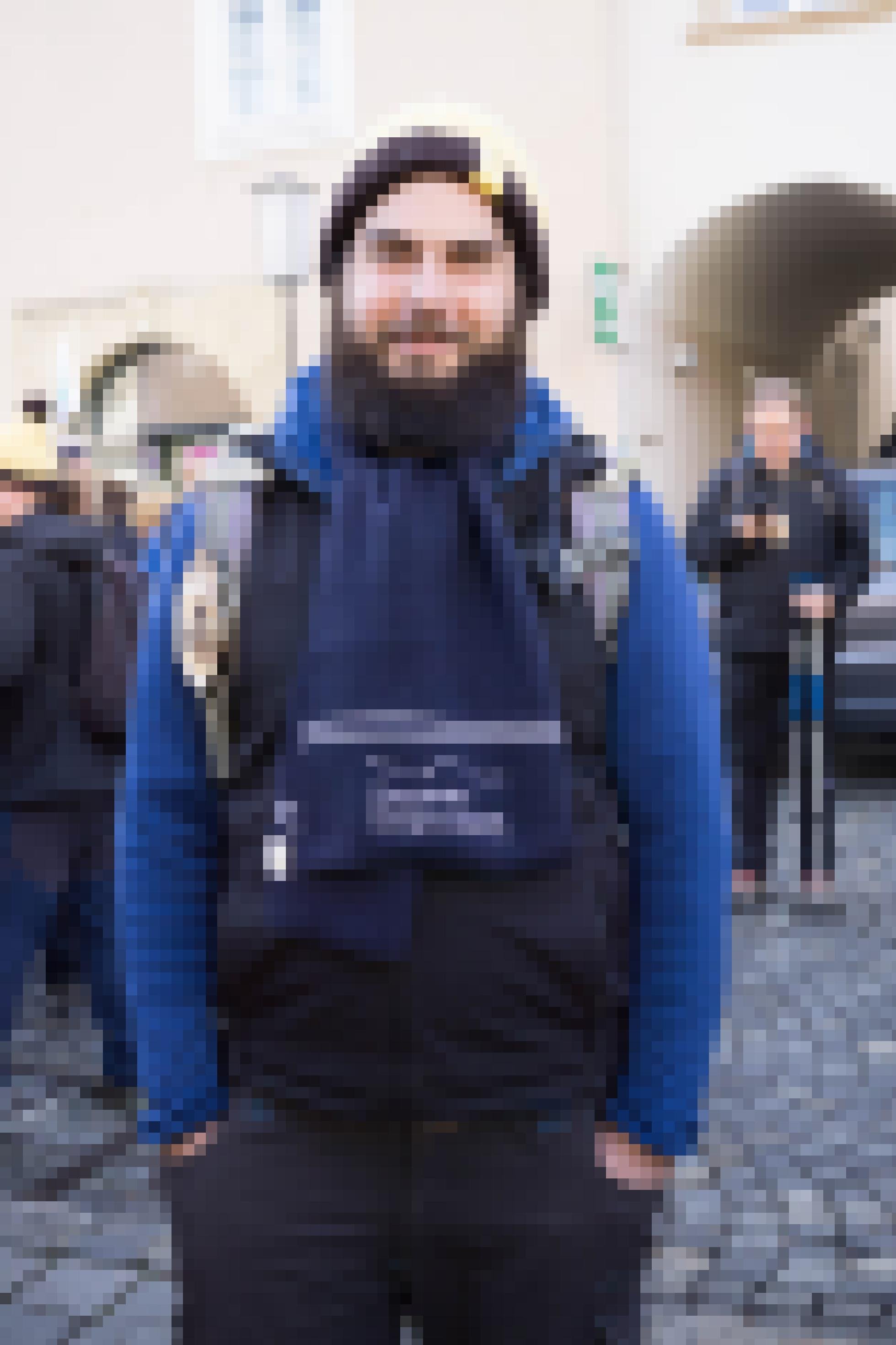 Mann mit Vollbart, Mütze und Schal mit Aufschrift "Moja Mura".
