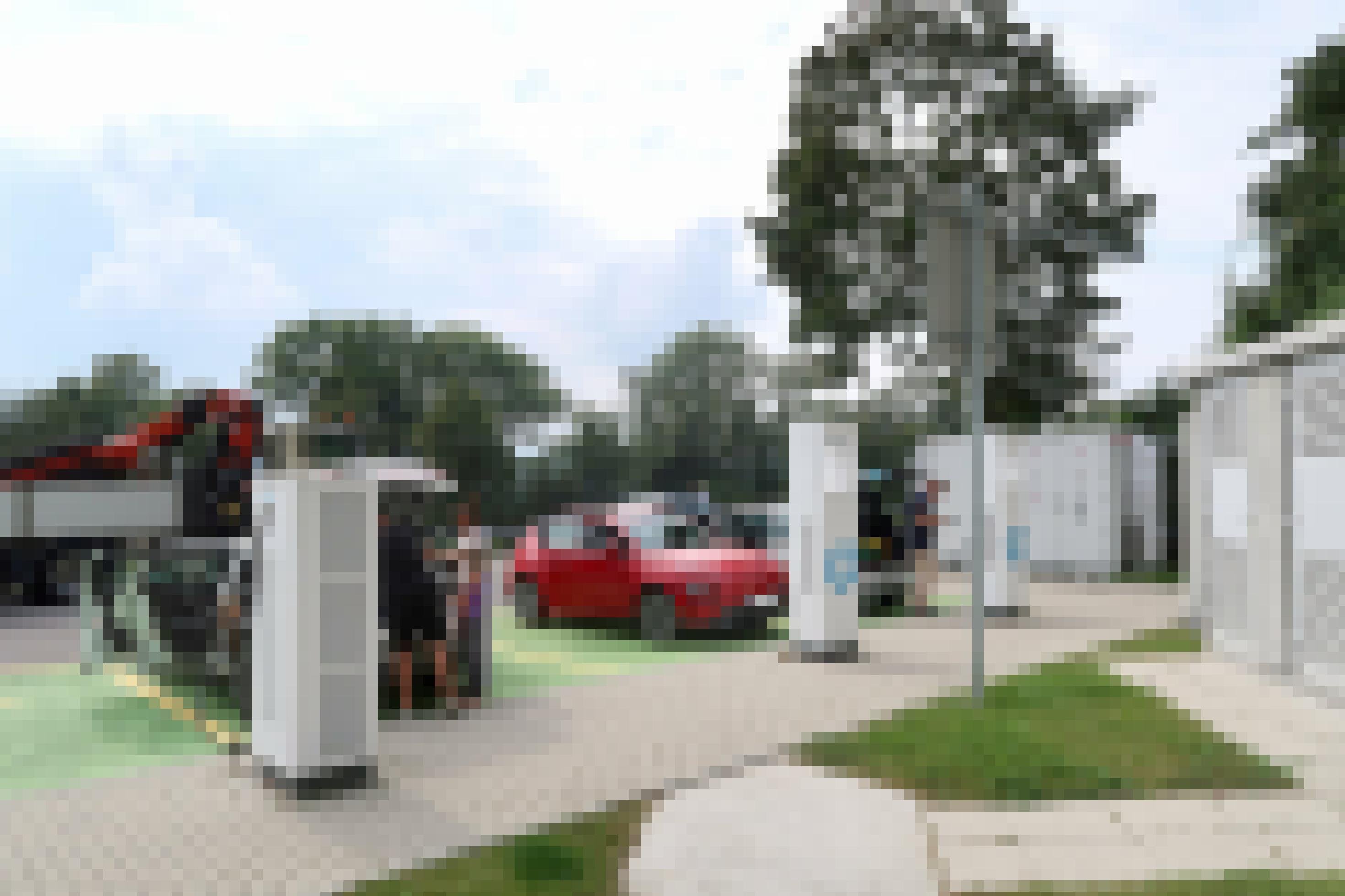 Drei Elektroautos laden Strom auf einem Parkplatz.