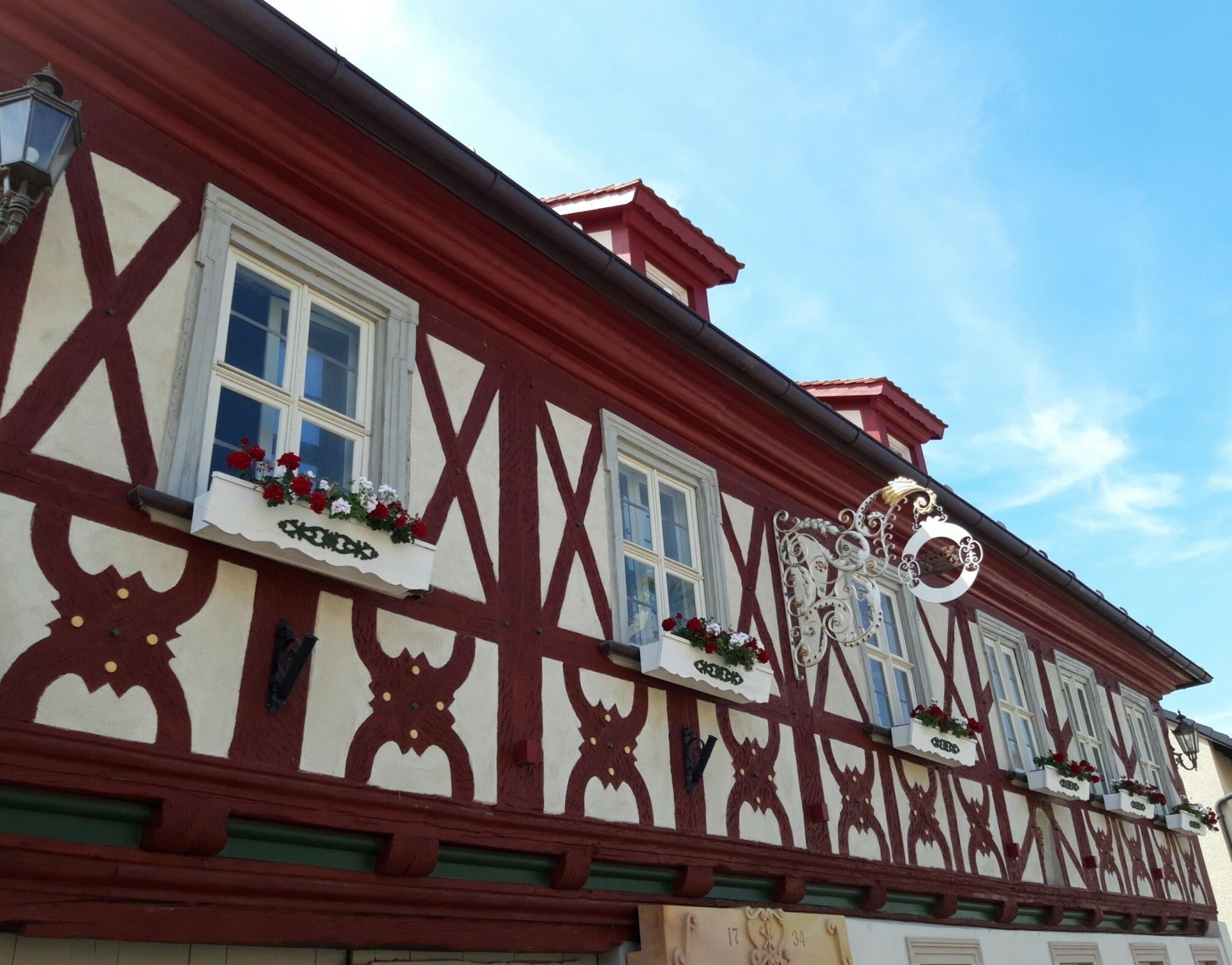 Sauber in rot gestrichen, korrespondiert das Holz der Außenfassade farblich mit den Geranien unter den kleinen schmucken Fenstern.