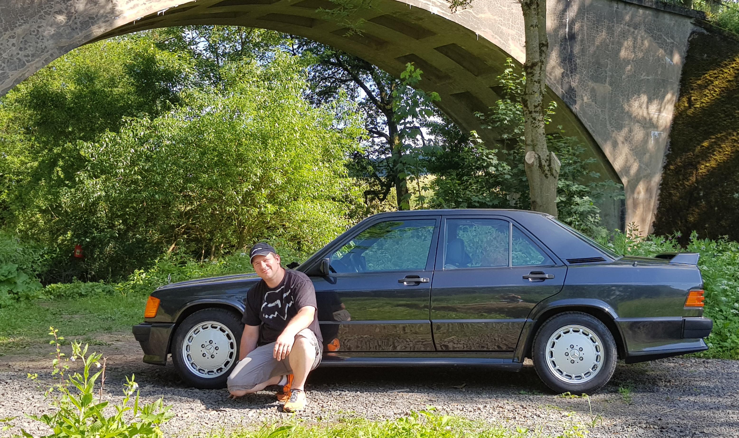 Steffen Lich kniet vor einem roten Mercedes 190 aus den 1980-er Jahren