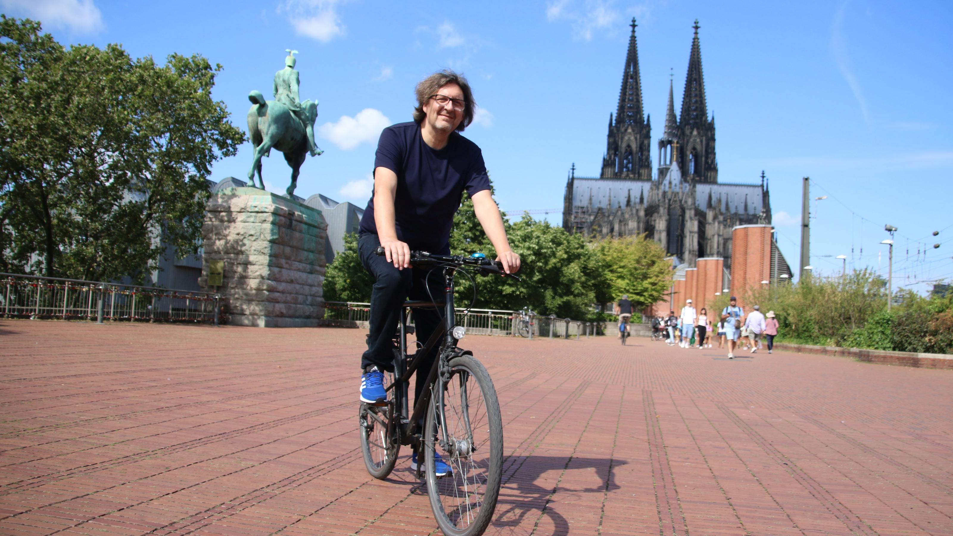 Reinhold Goss fährt Fahrrad hinterm Kölner Dolm