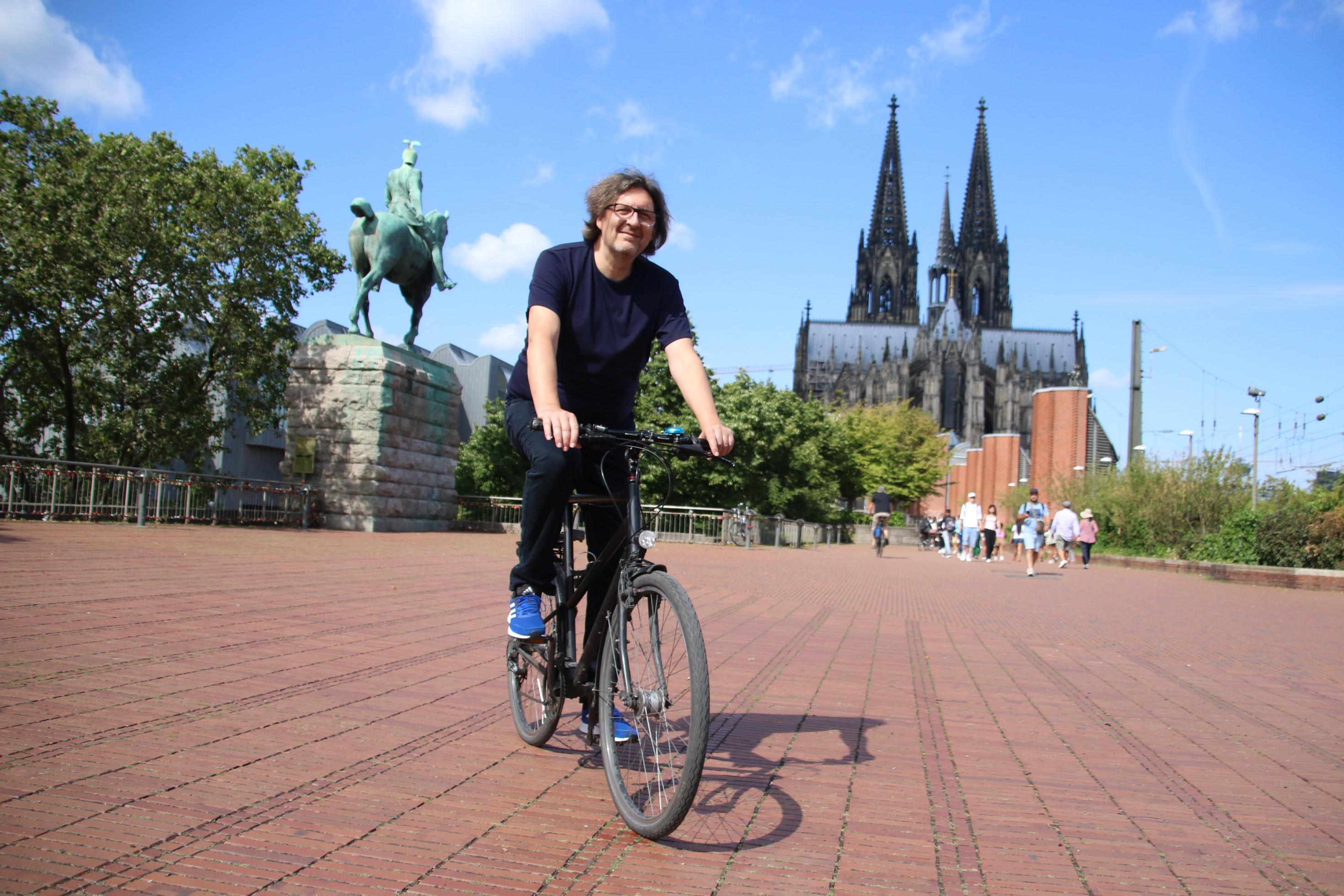 Reinhold Goss fährt Fahrrad hinterm Kölner Dolm