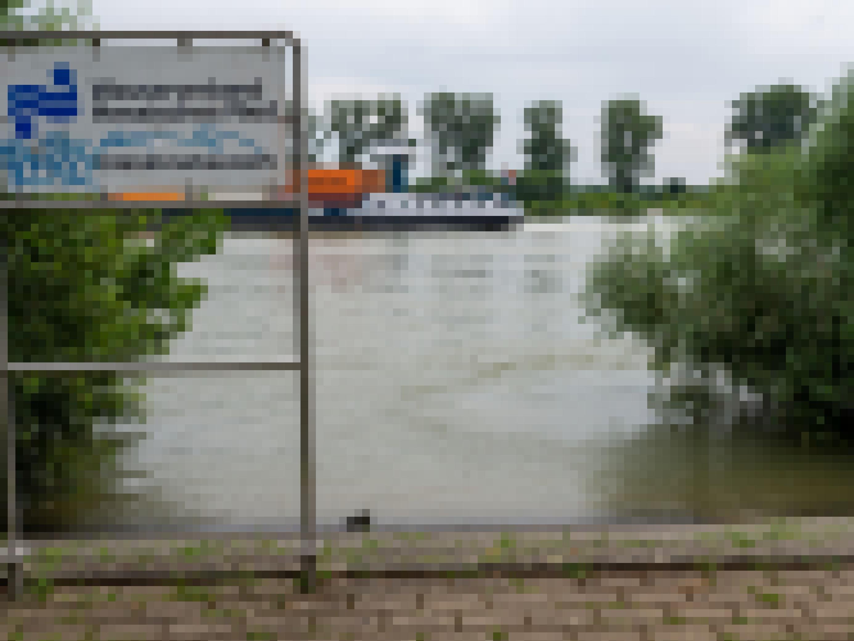 Schild „Entnahmebauwerk“ direkt am Rheinufer, Auf dem Fluss fährt ein Schiff zum linken Bildrand