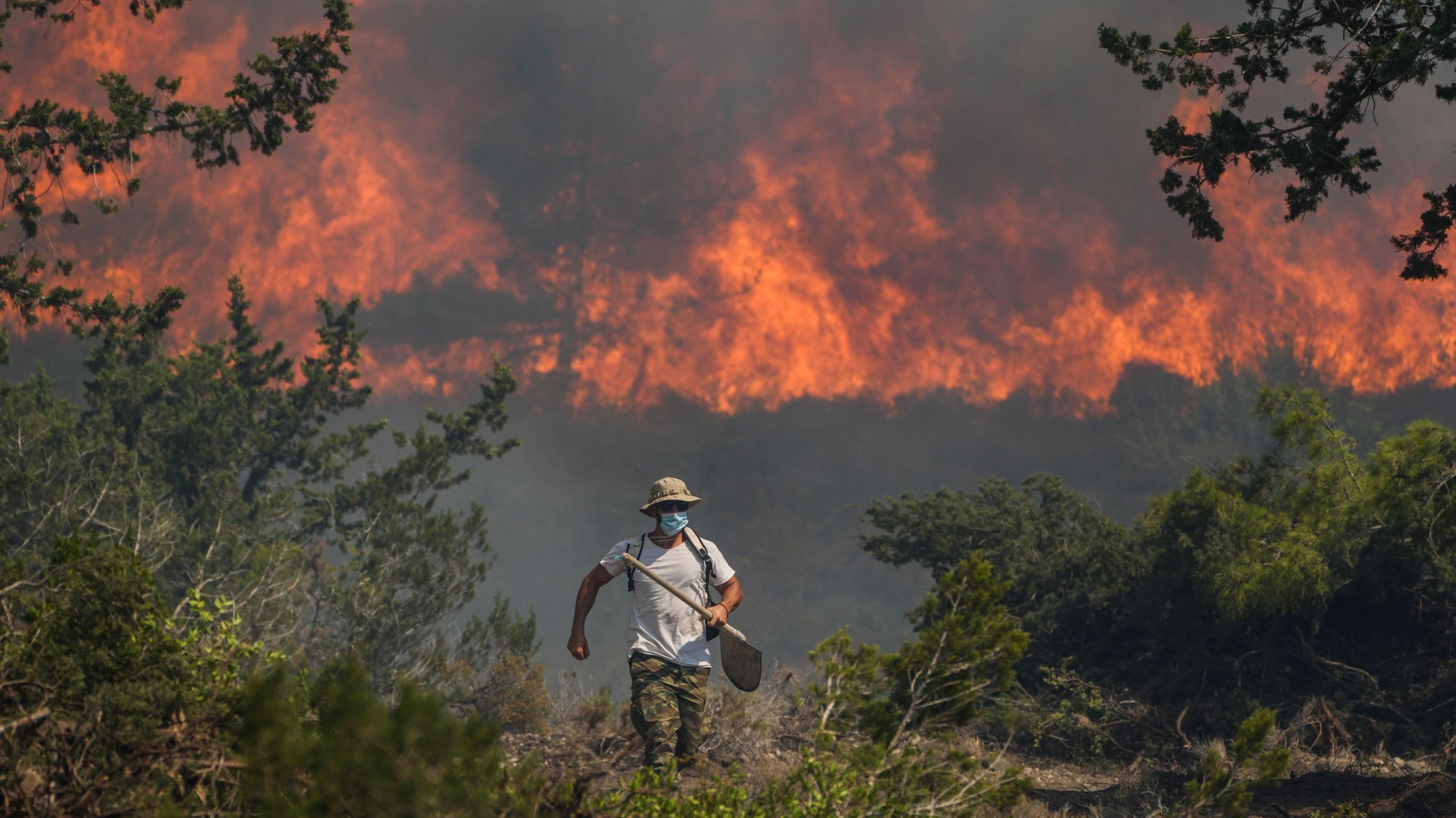 Ein Mann mit Tuch vor dem Mund flieht vor dem Waldbrand auf Rhodos