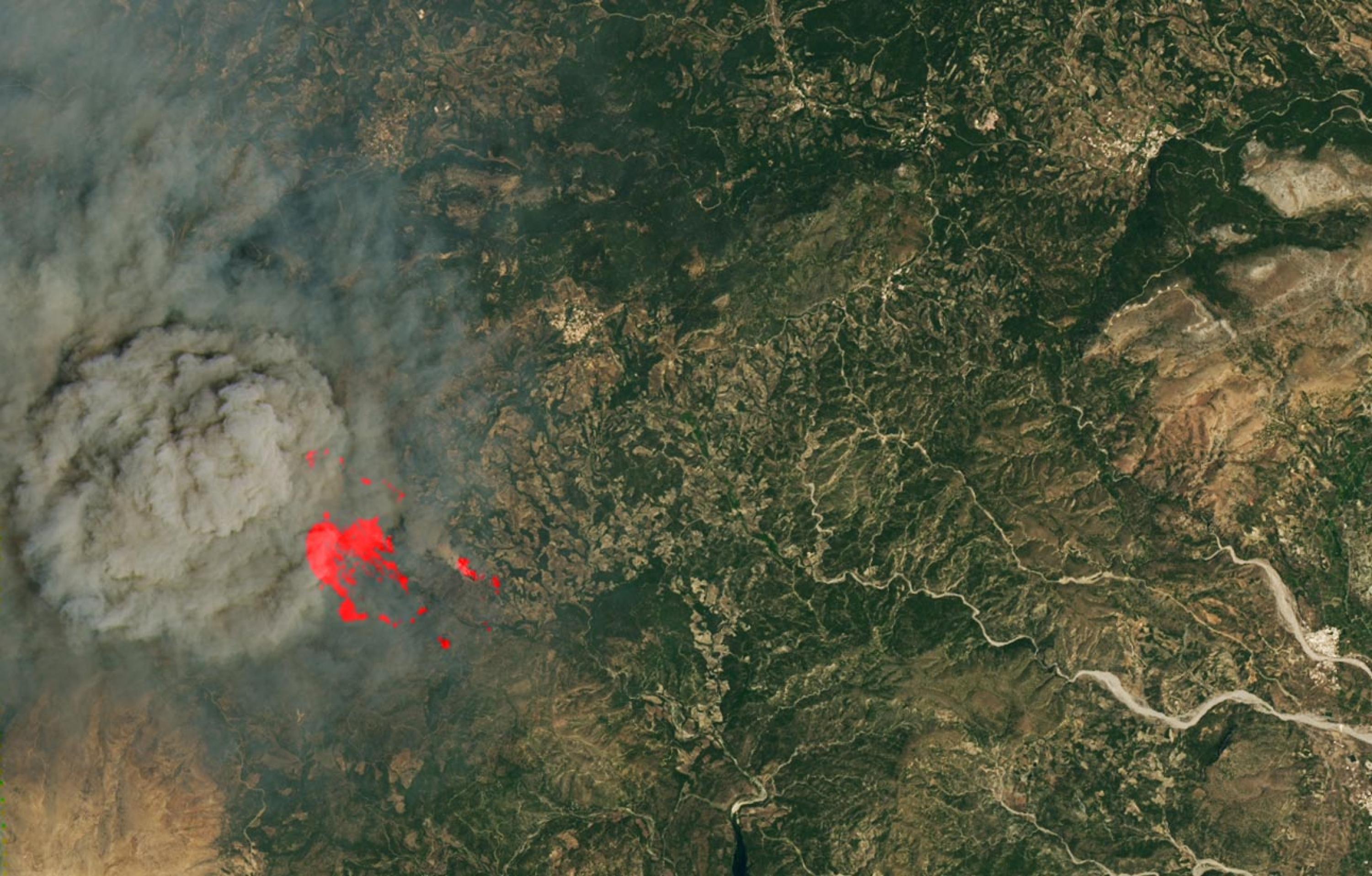 Satellitenfoto von Teilen Rhodos mit großer Rauchwolke links und rechts daneben rot hervorgehoben einer Waldbrandfläche
