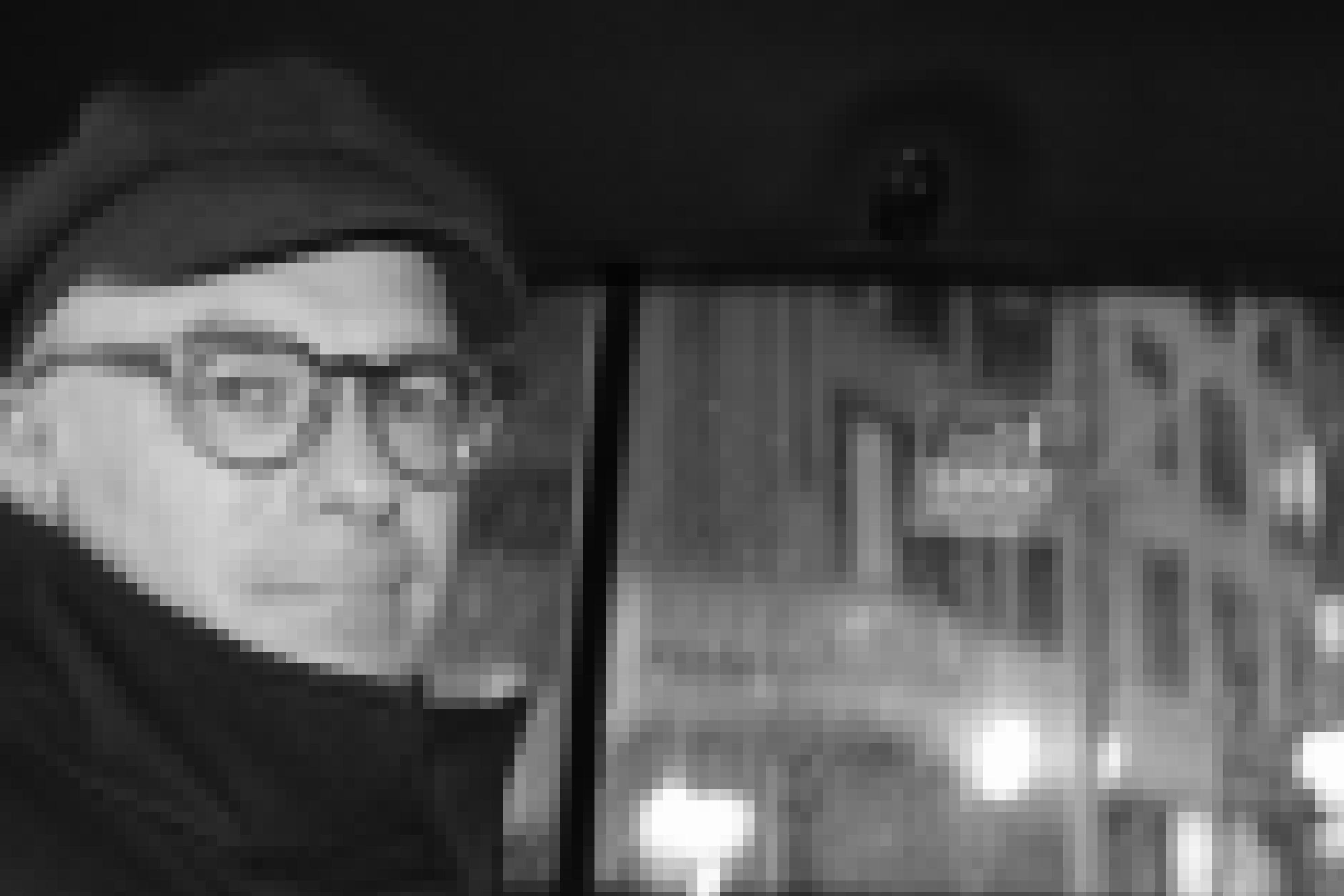 Schwarz-weiß Aufnahme von Andreas von Bubnoff. Er sitzt bei Regen in einem Auto und trägt eine Mütze, Brille und einen Mantel.