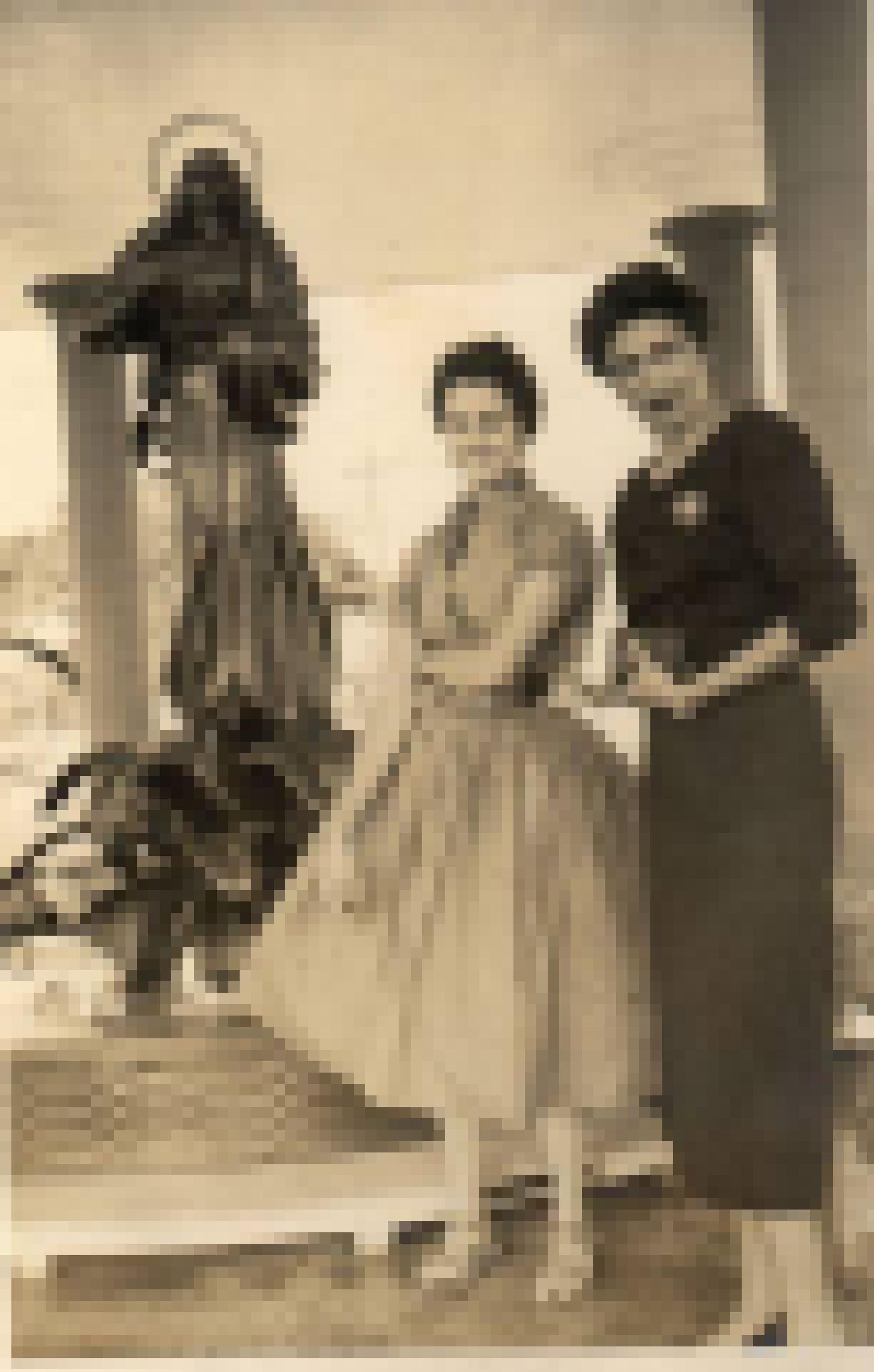 Zwei elegant gekleidete Frauen vor einem Brunnen mit der Skulptur einer Heiligenfigur