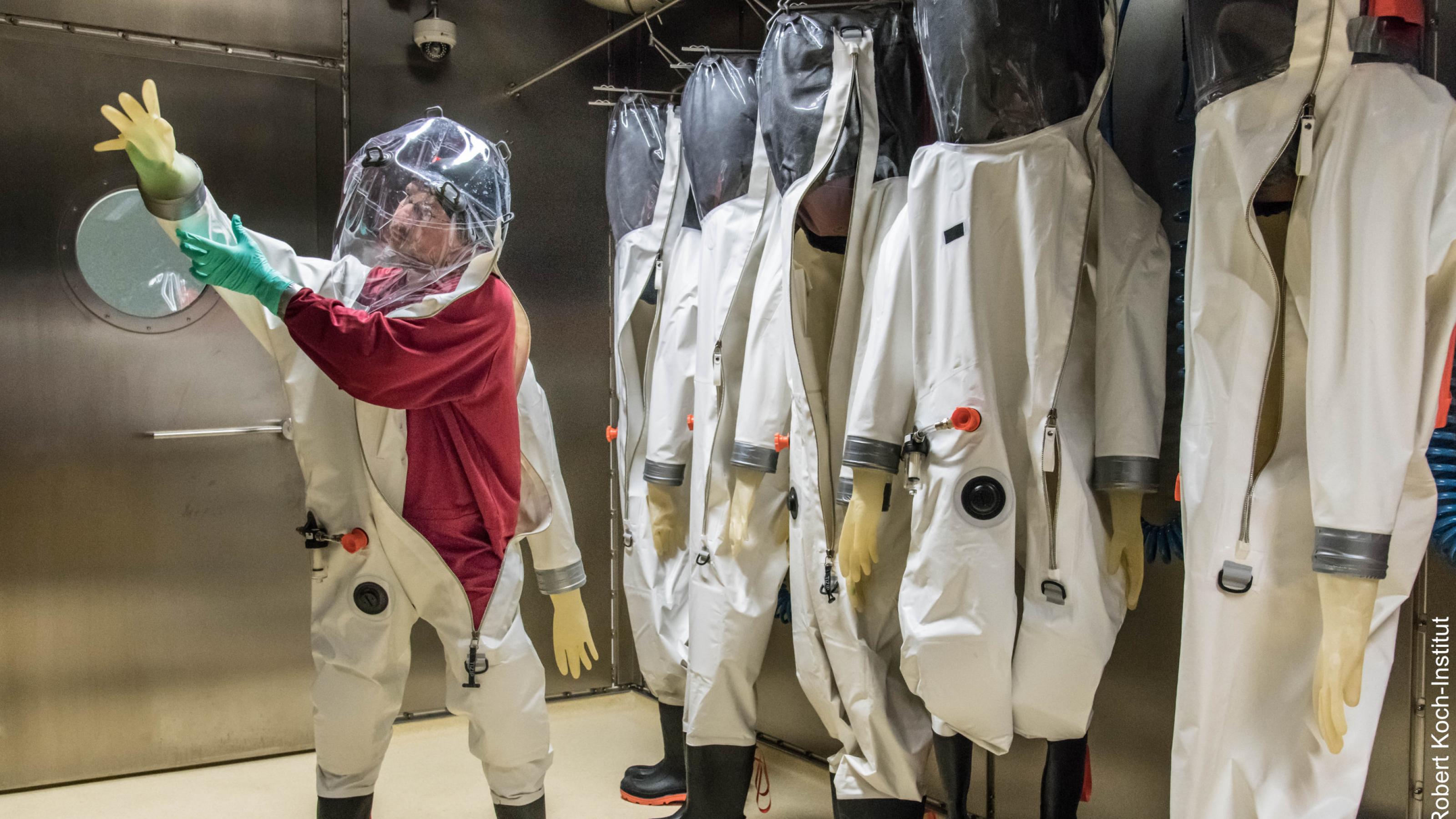 Ein Mitarbeiter des Robert Koch-Instituts beim Anziehen eines Ganzkörper-Schutzanzuges auf dem Weg ins Hochsicherheitslabor.