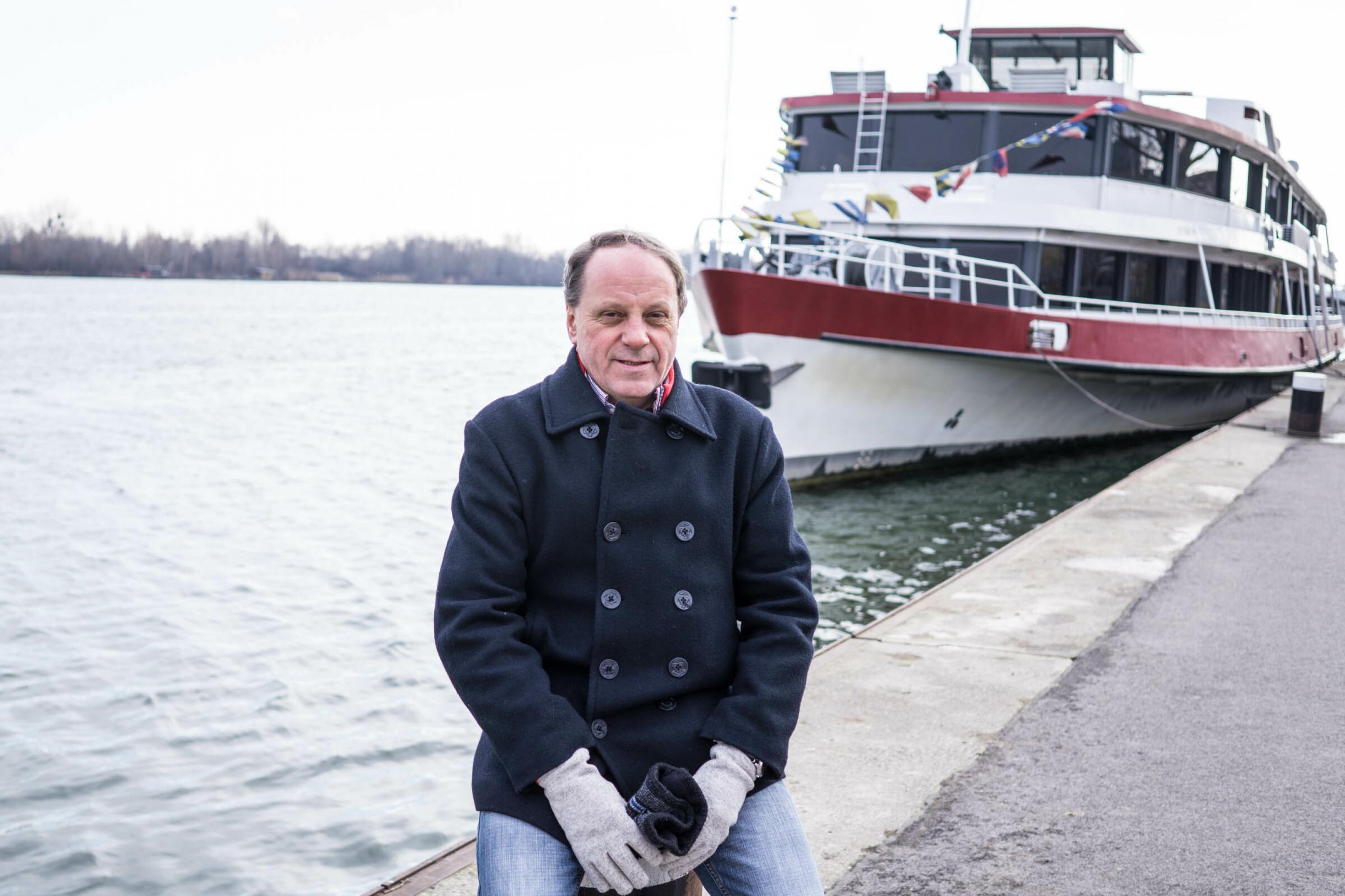 Ein Mann sitzt im Hafen der Donau in Wien auf einem Poller.