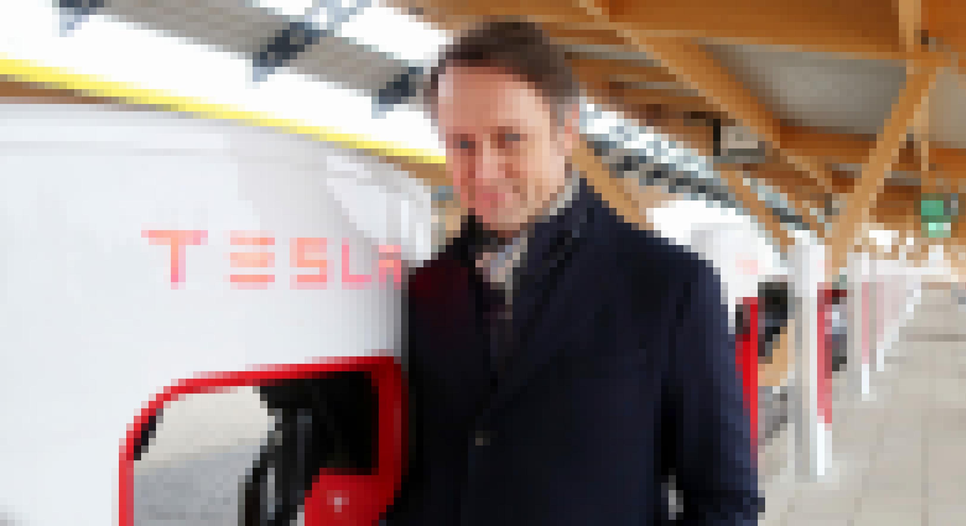 Ein Mann lehnt an einer Schnellladesäule für Tesla-Autos.