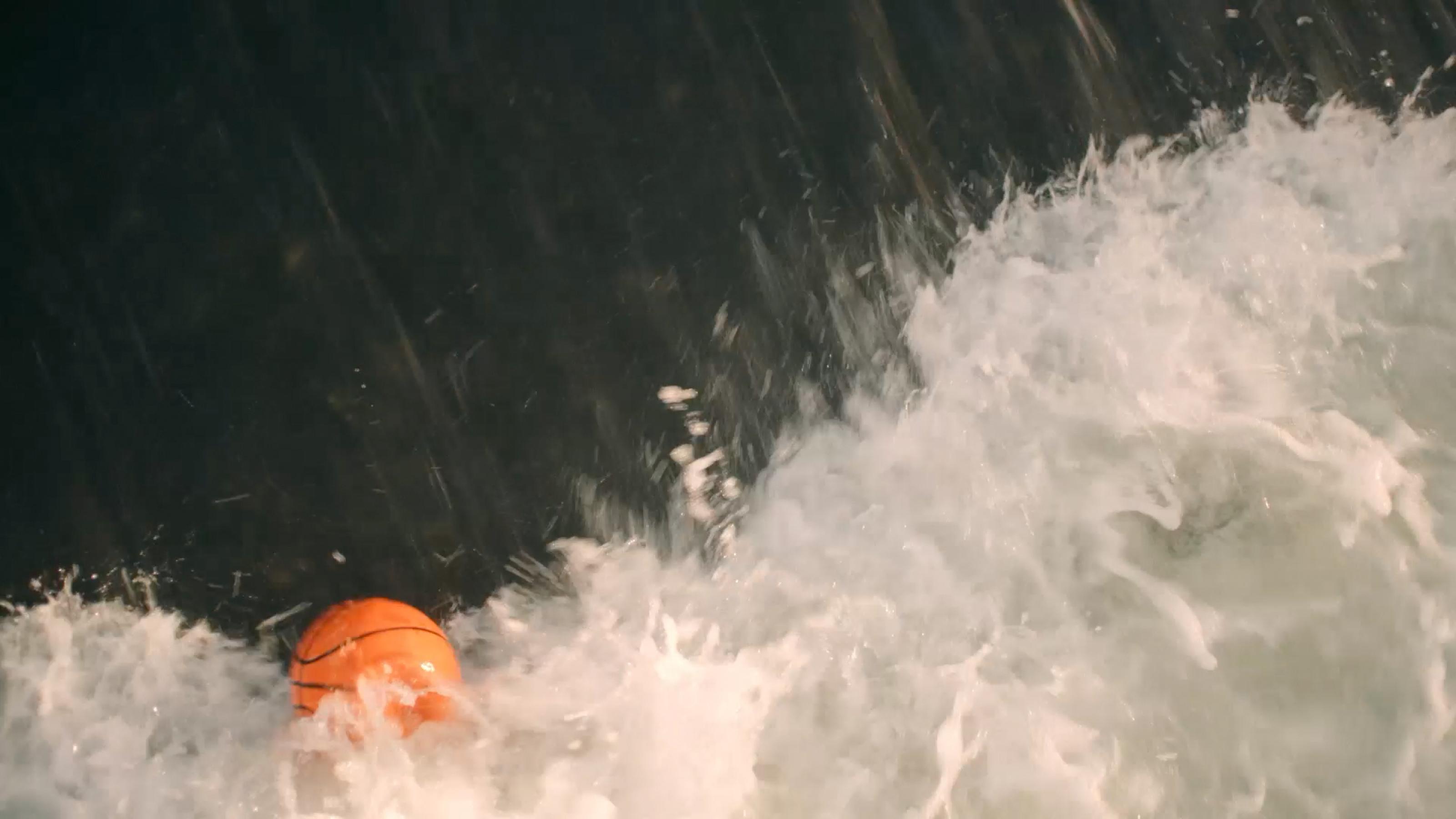 Ein orangefarbener Ball in der Gischt eines Flusses.