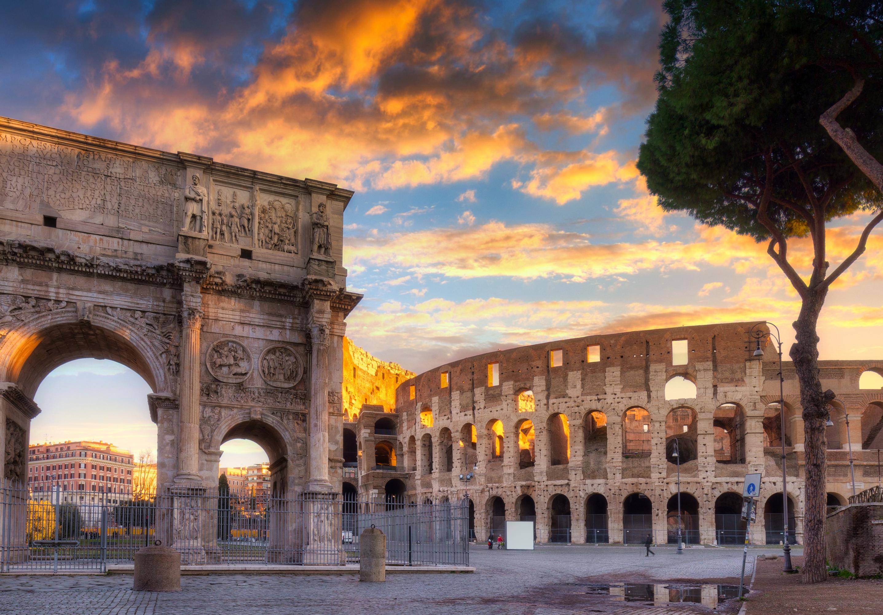 Unter dramatischem, rot-sonnig-beleuchtetem Wolkenhimmel ragen die altehrwürdigen, prachtvollen Gemäuer am noch menschenleeren Forum Romanum auf.